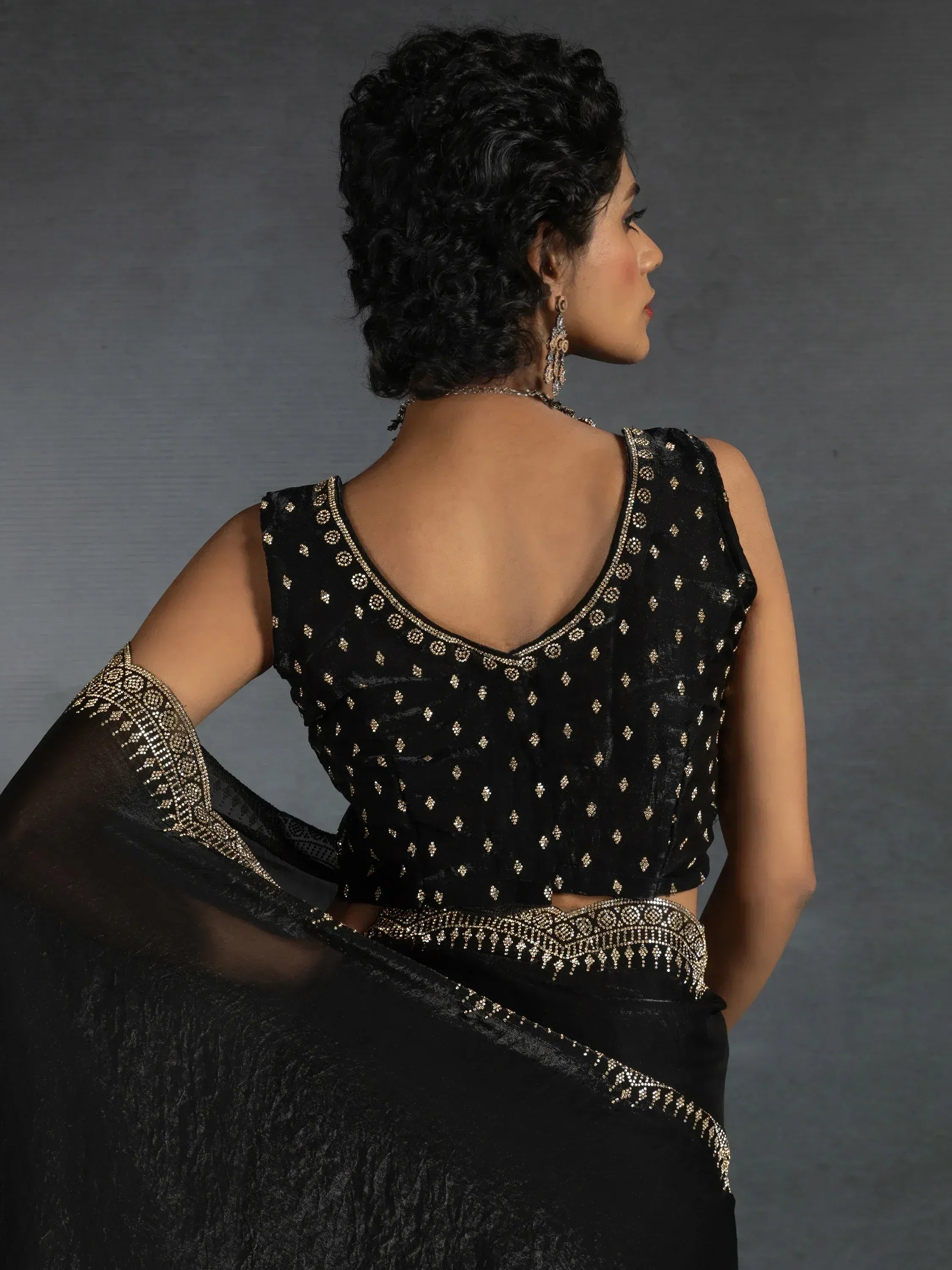 Black saree with gold embroidery and sleeveless blouse, showcasing elegant ethnic wear design