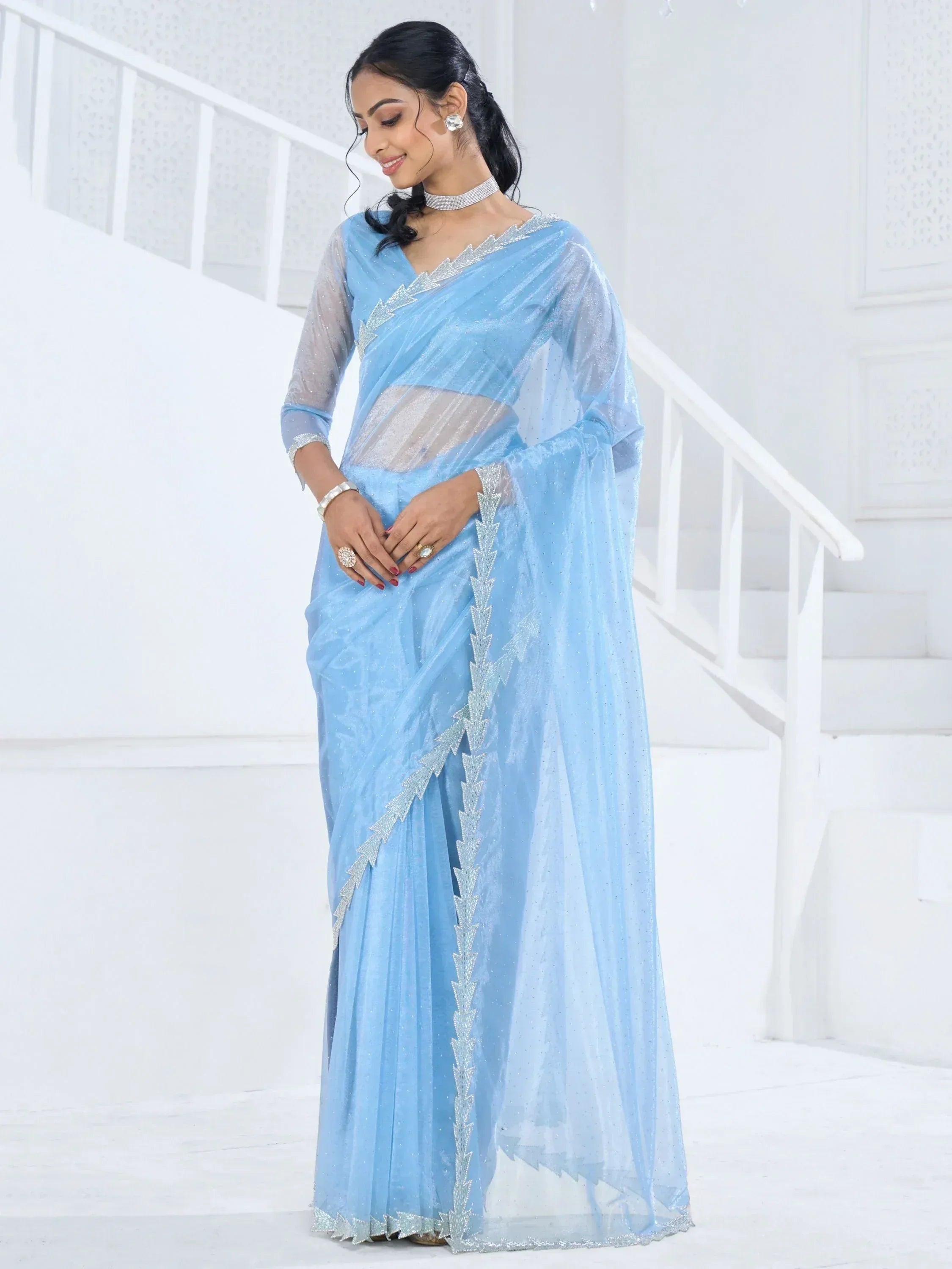 Light blue designer saree with silver embellishments and sheer blouse, perfect for ethnic occasions