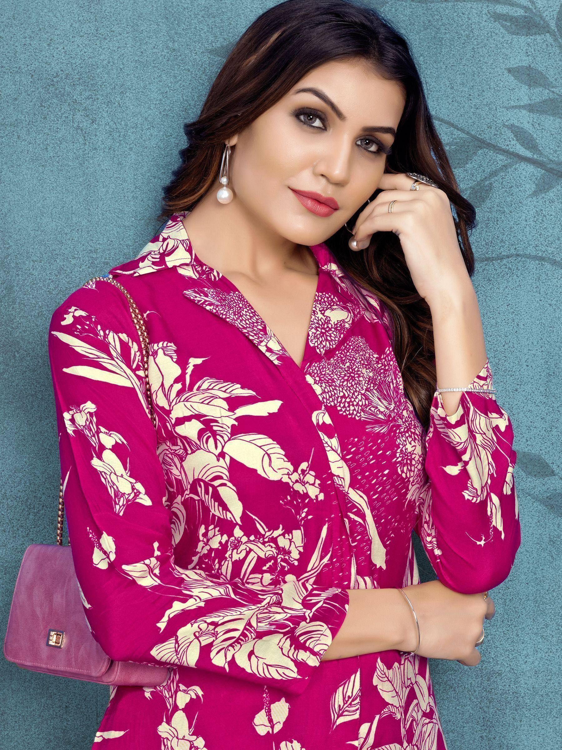 Woman in magenta floral ethnic gown with pearl earrings and purple handbag, styled for Indian fashion