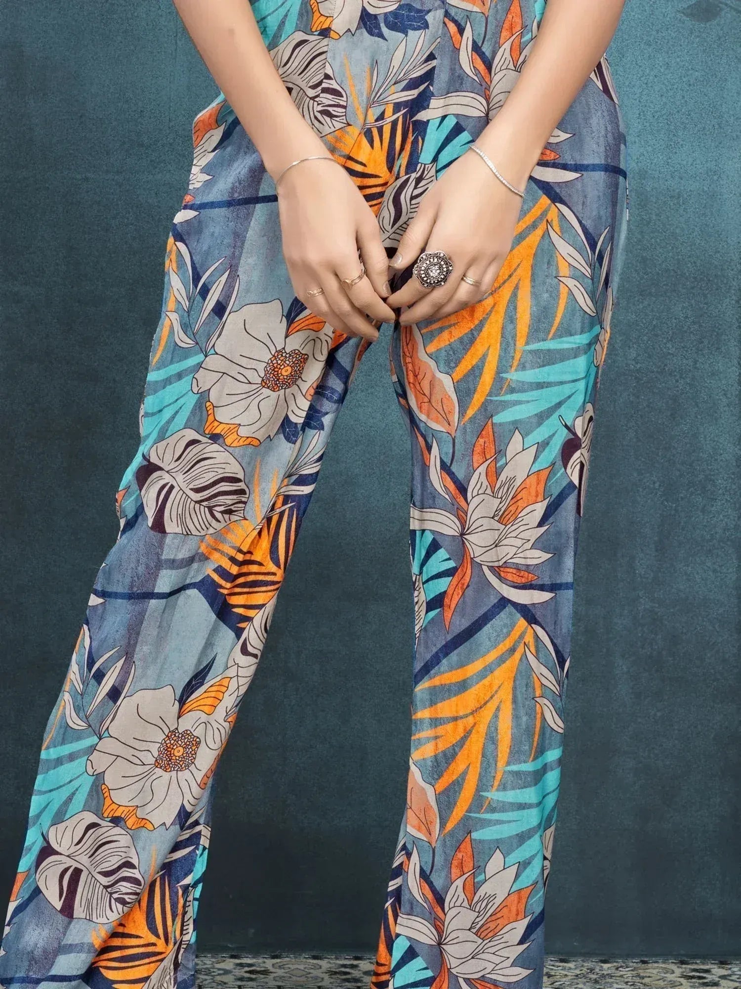 Woman wearing wide-leg floral print palazzo pants in blue, orange, and cream tones