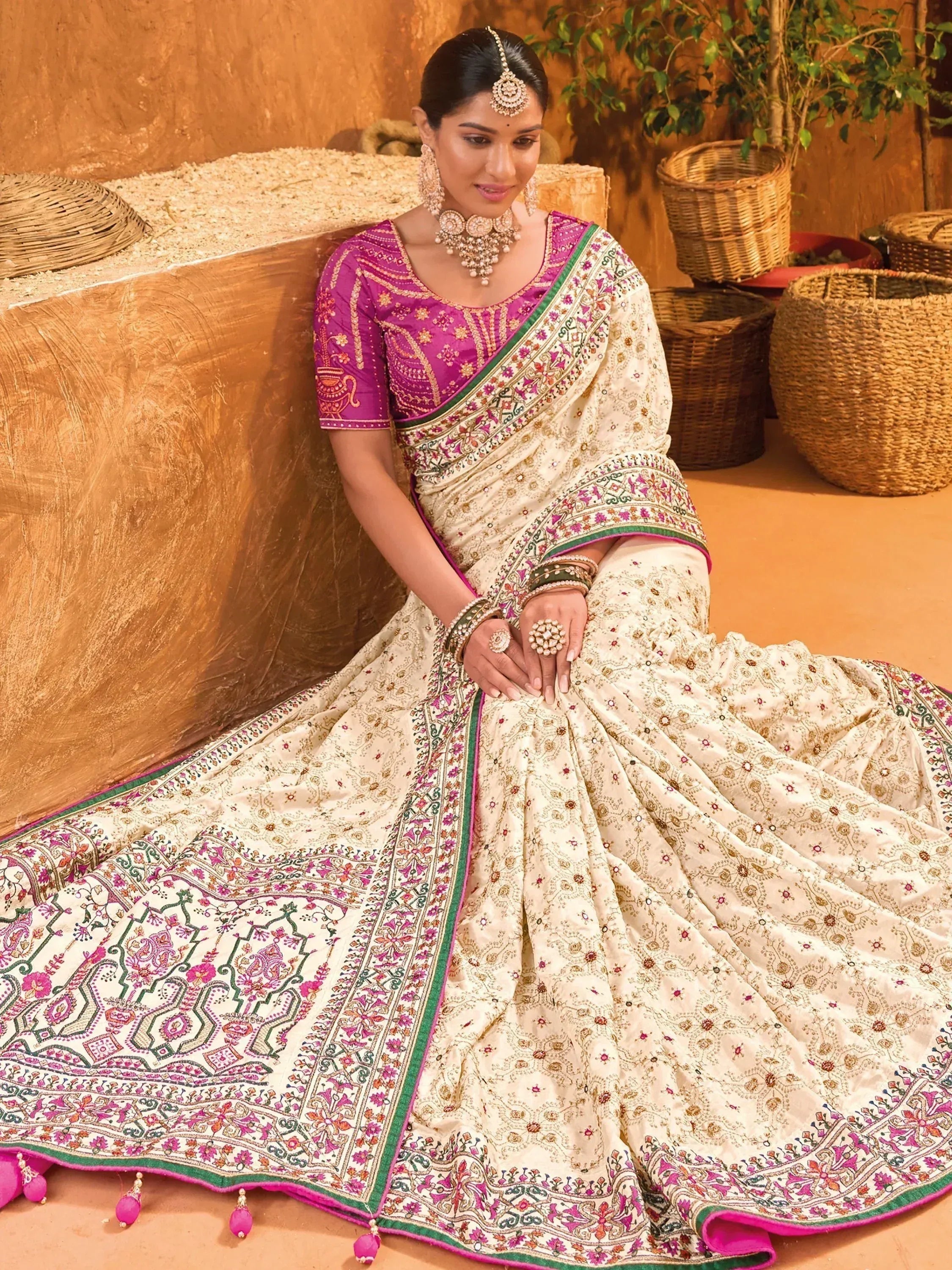 Elegant cream and pink embroidered saree with traditional Indian jewelry, perfect for festive occasions.
