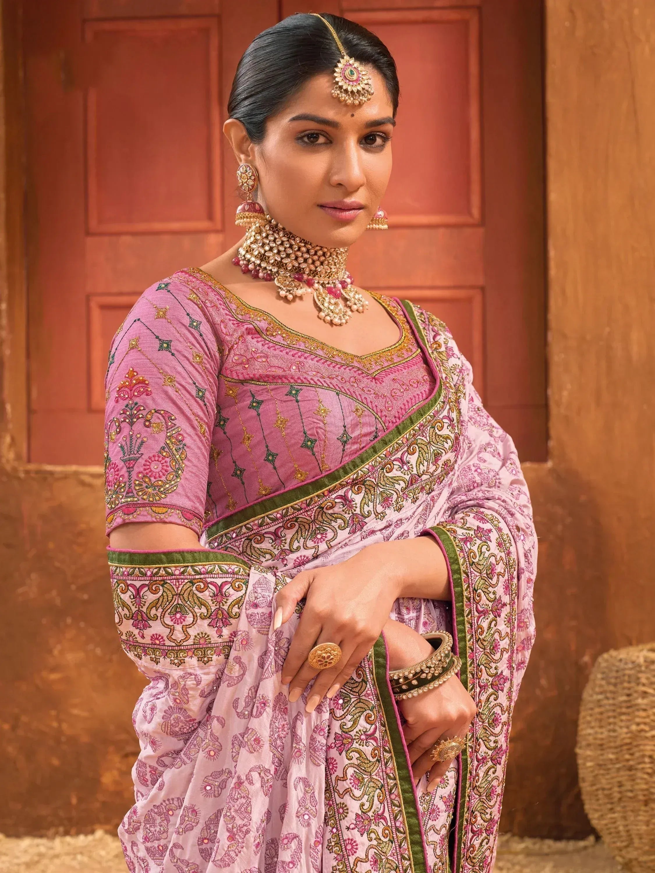 Woman in pink embroidered saree with gold jewelry, traditional Indian ethnic wear