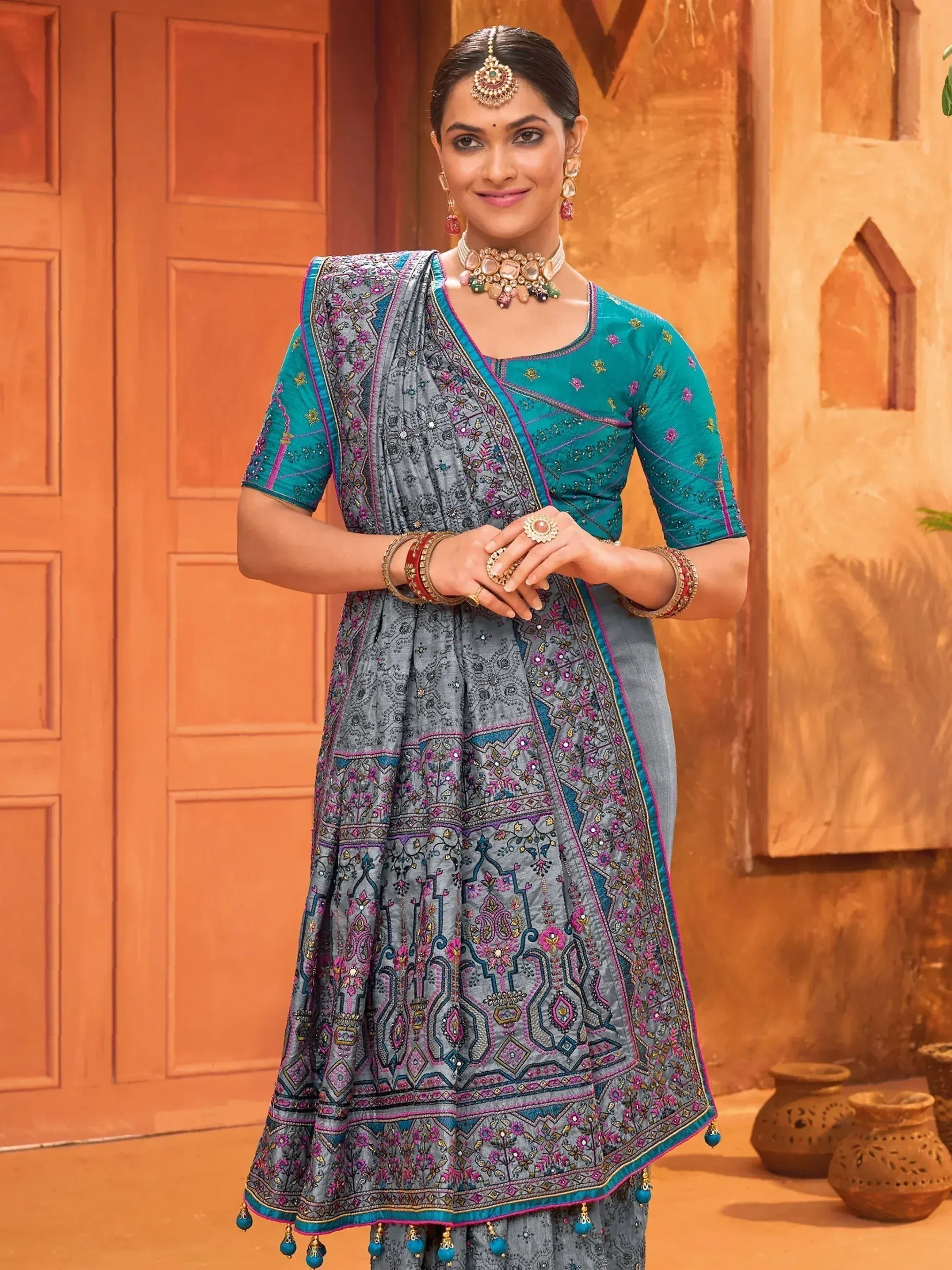 Elegant grey and teal embroidered anarkali suit with traditional Indian jewelry, perfect for festive occasions.