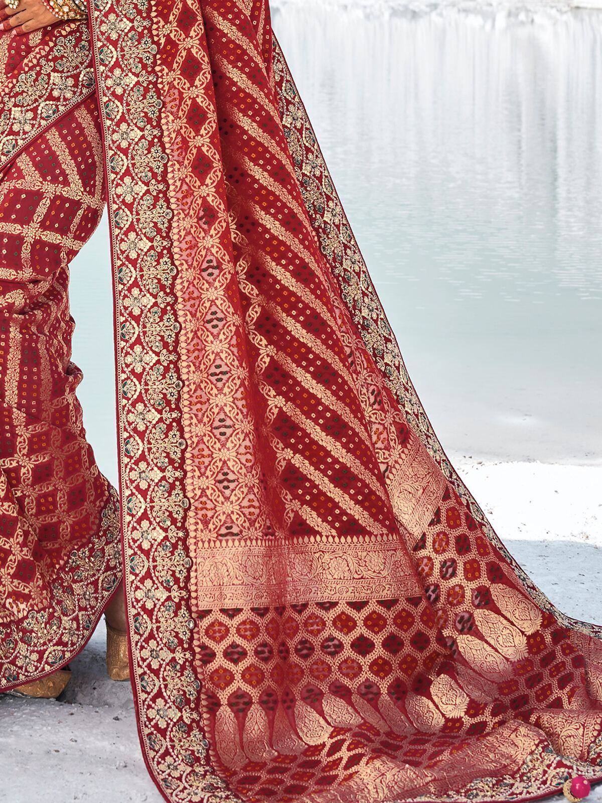 Red and gold designer saree with intricate floral and geometric patterns, perfect for ethnic occasions.