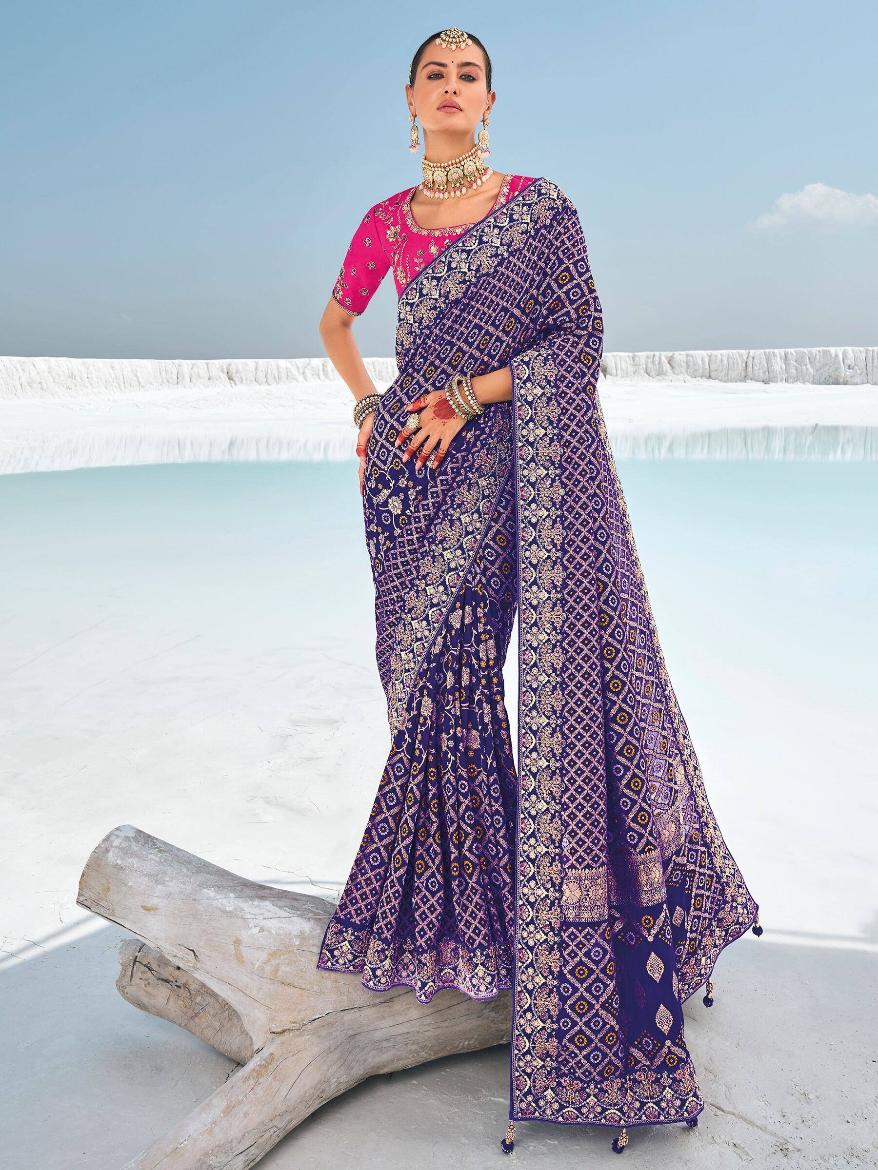Woman in purple printed saree with pink blouse, traditional Indian ethnic wear, standing by white terraces