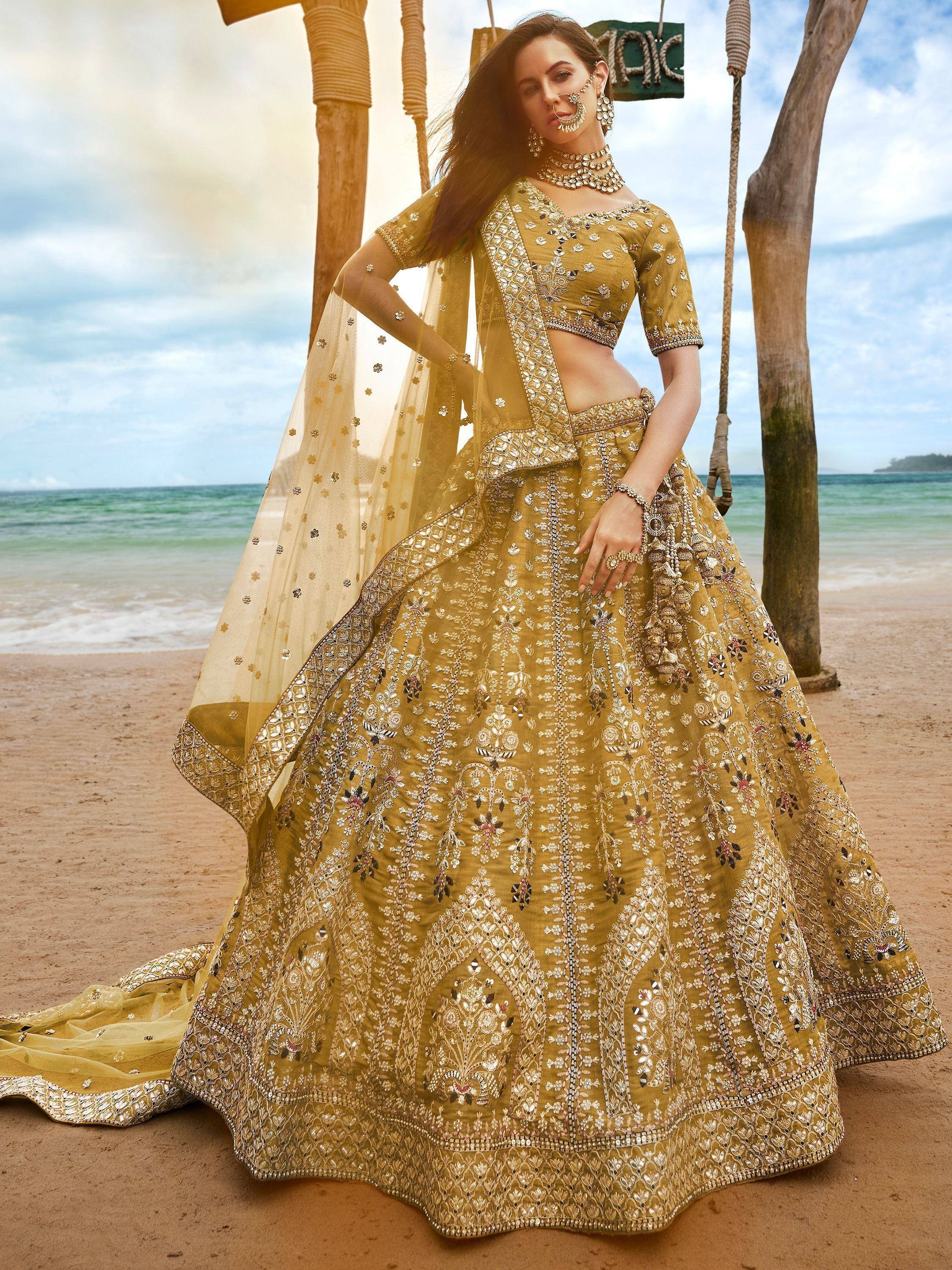 Golden embroidered lehenga choli on beach, Indian ethnic wear with mirror work and dupatta