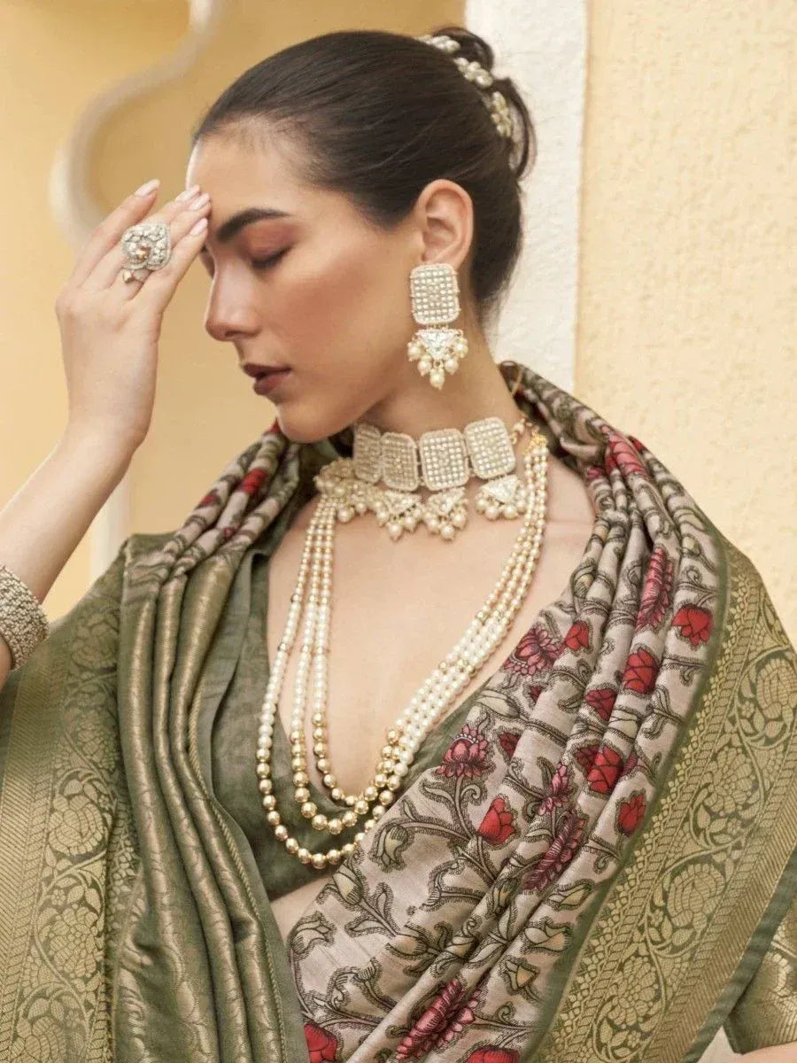 Elegant woman in olive green ethnic saree with floral border, pearl jewelry, and statement earrings