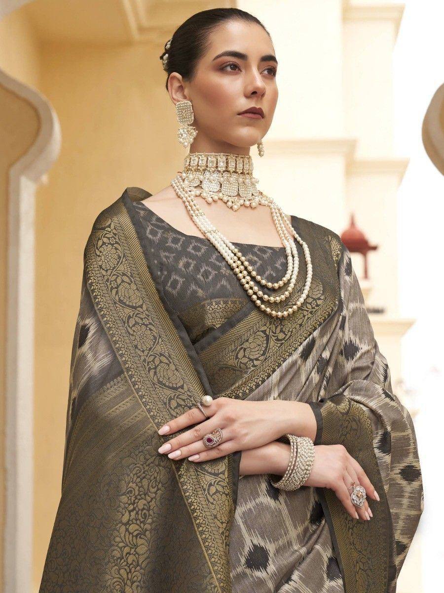 Elegant woman in designer saree with intricate patterns and pearl jewelry, showcasing ethnic Indian wear.