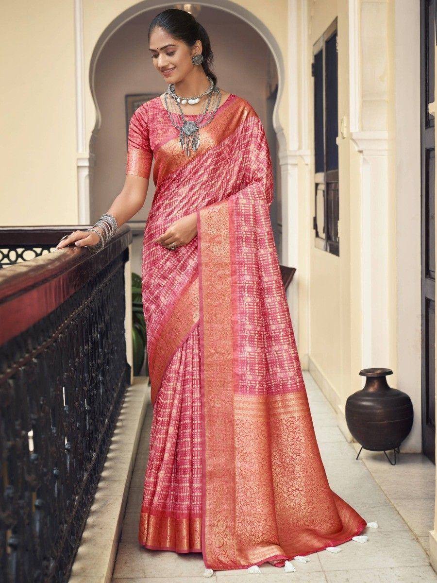 Pink and orange designer saree with intricate patterns, worn with traditional jewelry on a heritage balcony