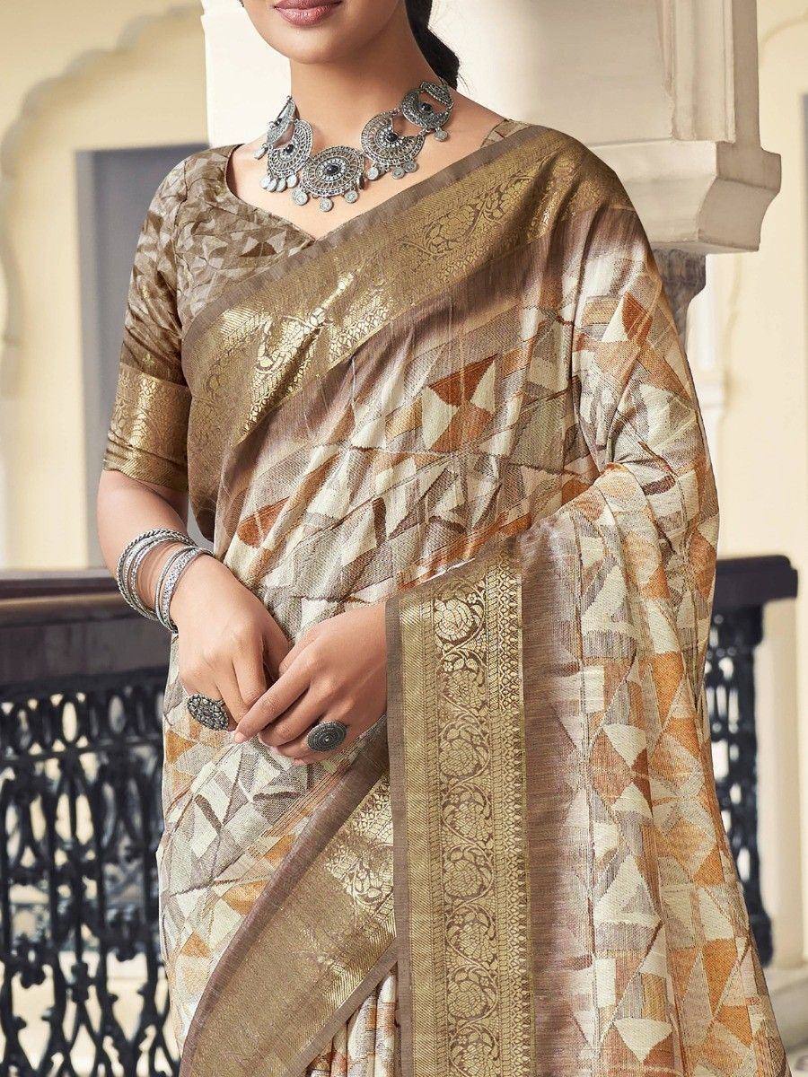 Elegant beige and gold geometric print saree with intricate border, paired with traditional silver jewelry