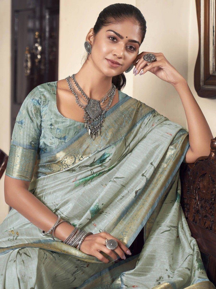 Woman in elegant light green printed saree with gold border, styled with traditional silver jewelry for ethnic occasions.