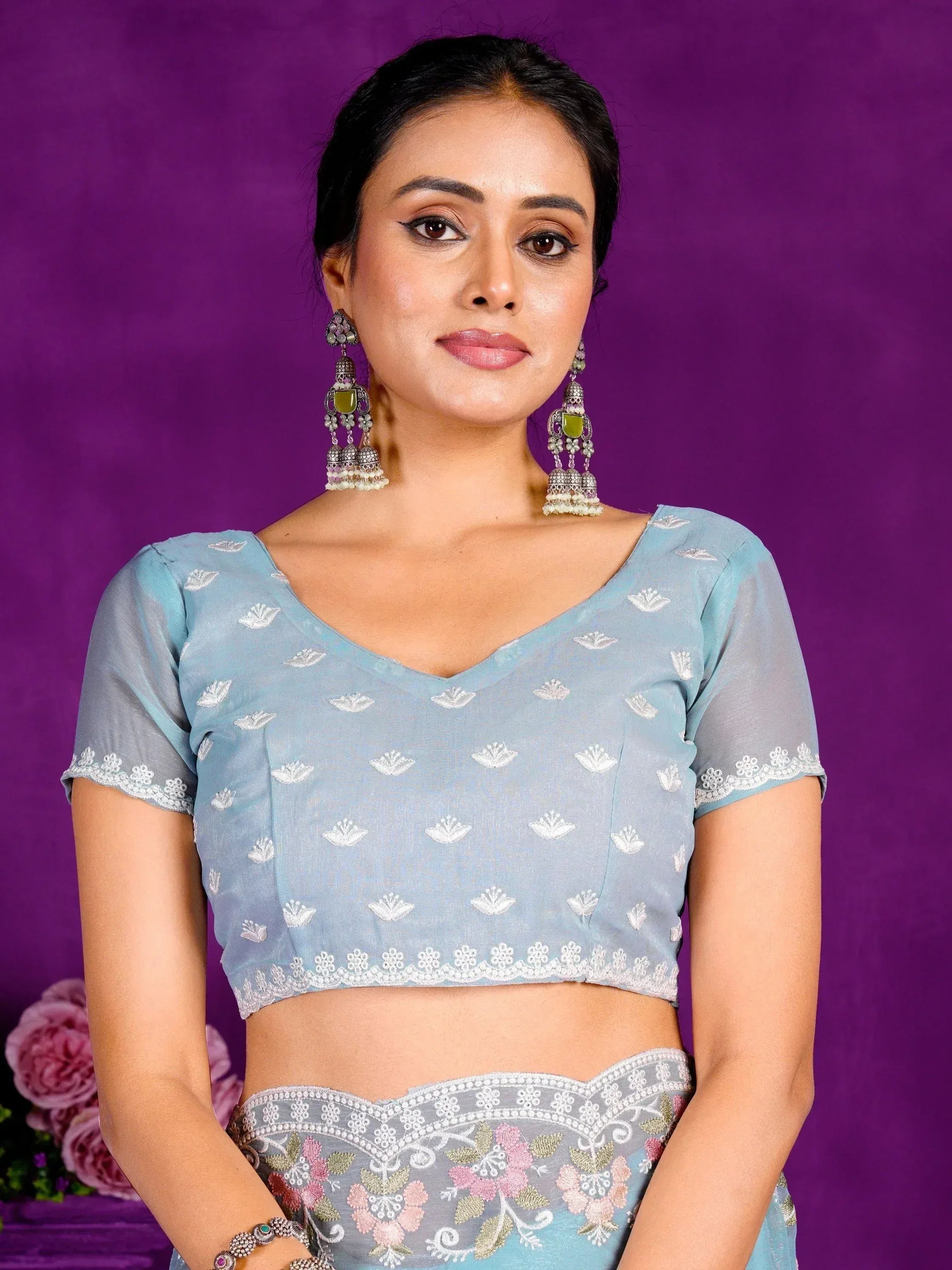 Light blue embroidered lehenga choli with floral motifs and lace trim, paired with statement earrings