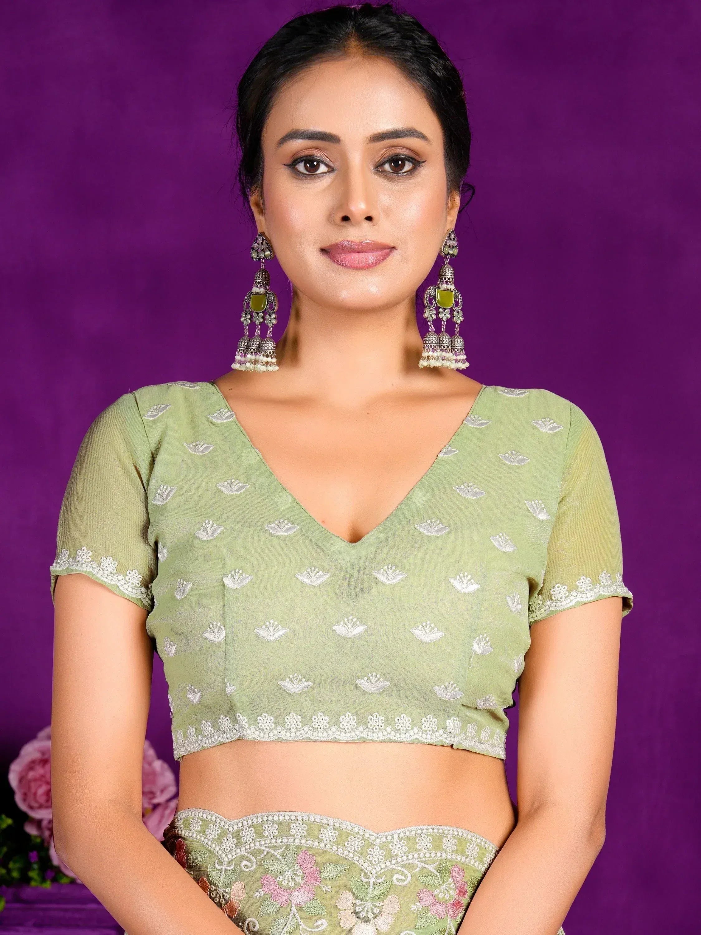 Green embroidered lehenga choli with floral motifs and matching jhumka earrings for Indian ethnic wear