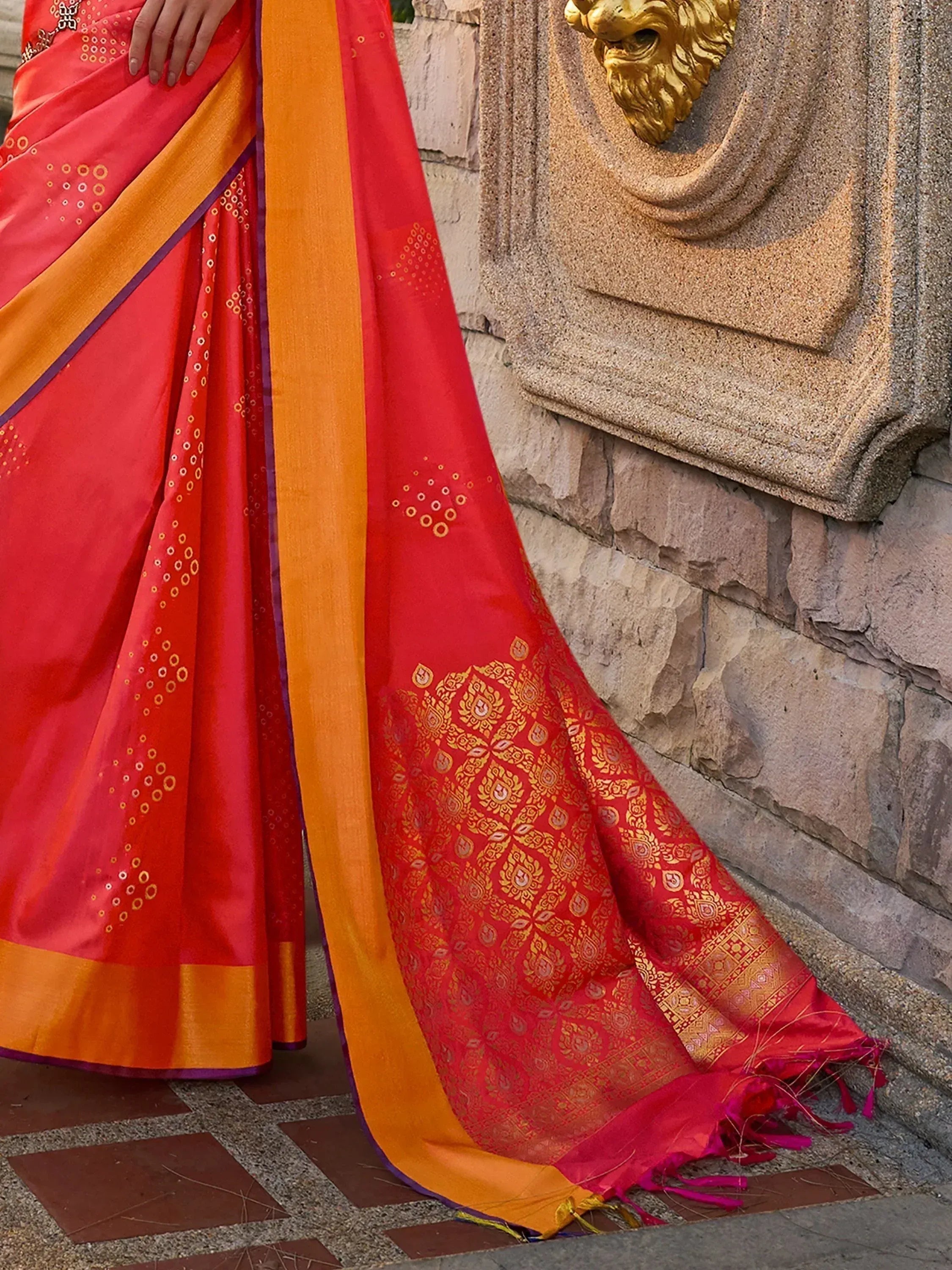 Vibrant red and orange ethnic saree with gold zari work, perfect for Indian celebrations