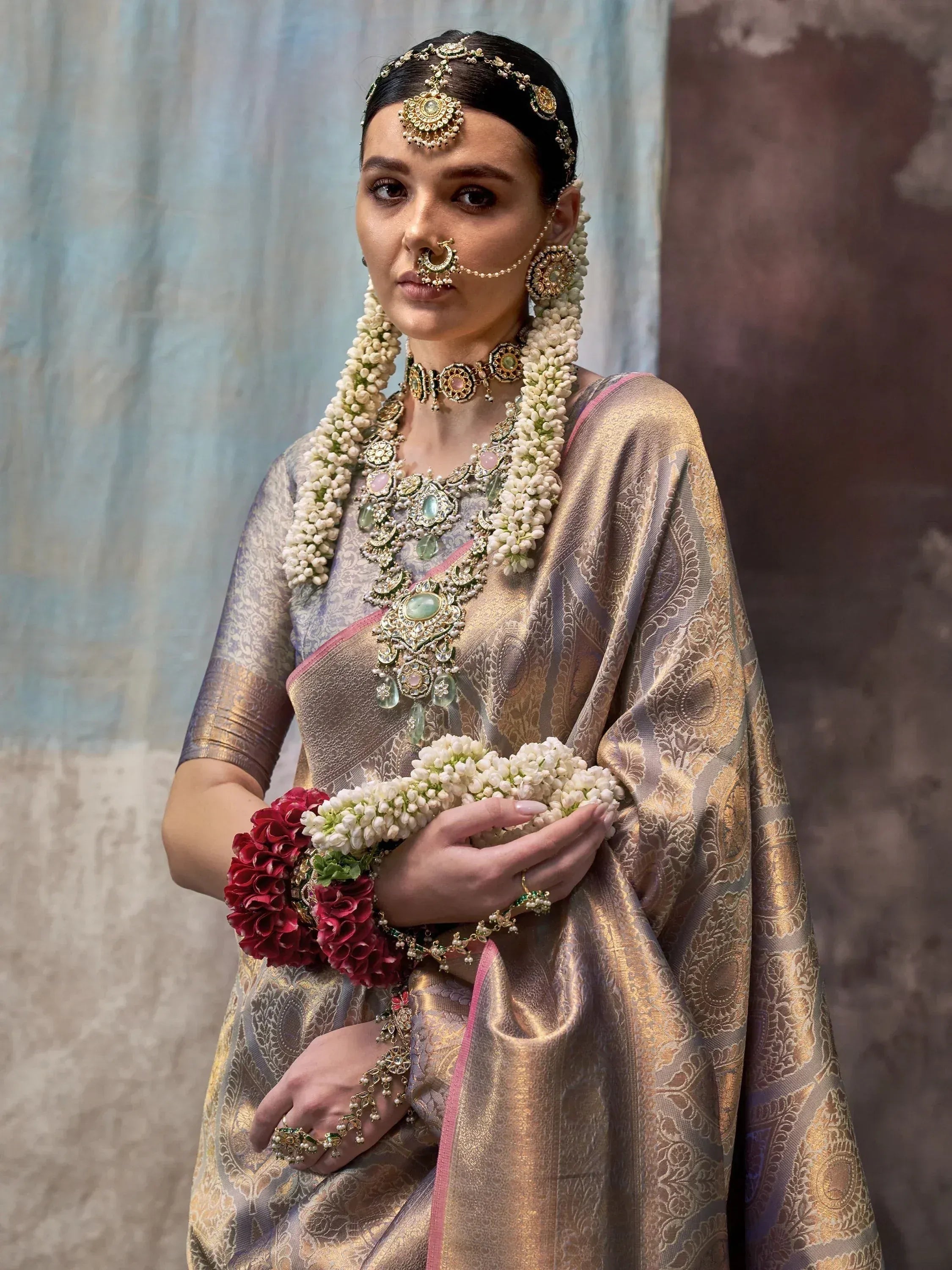 Woman in traditional Indian saree with gold embroidery, floral jewelry, and temple jewelry for wedding or festive occasions.