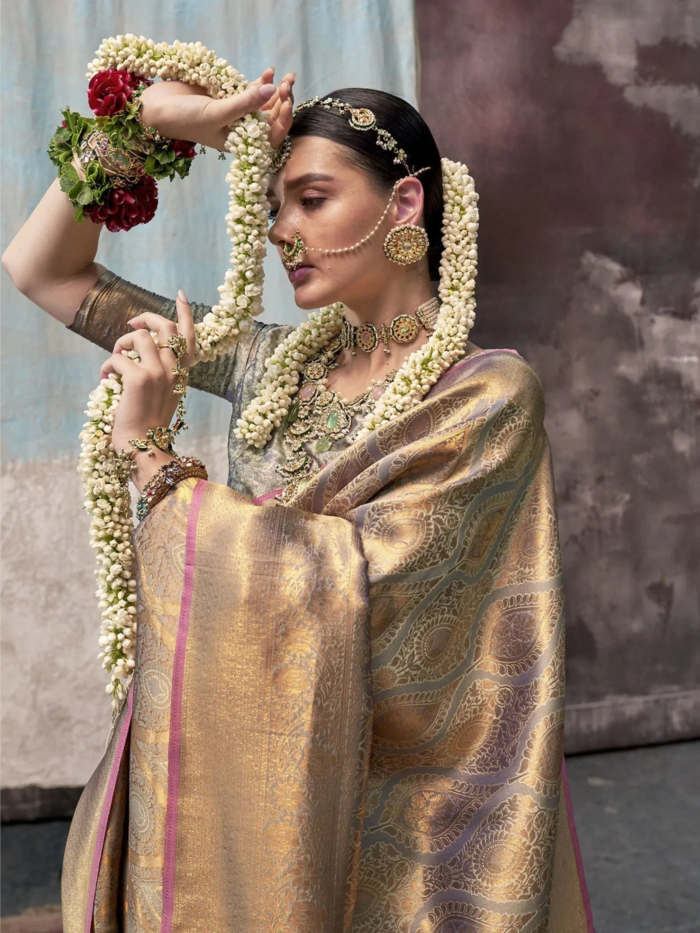 Woman in traditional Indian saree with gold embroidery, floral garlands, and temple jewelry