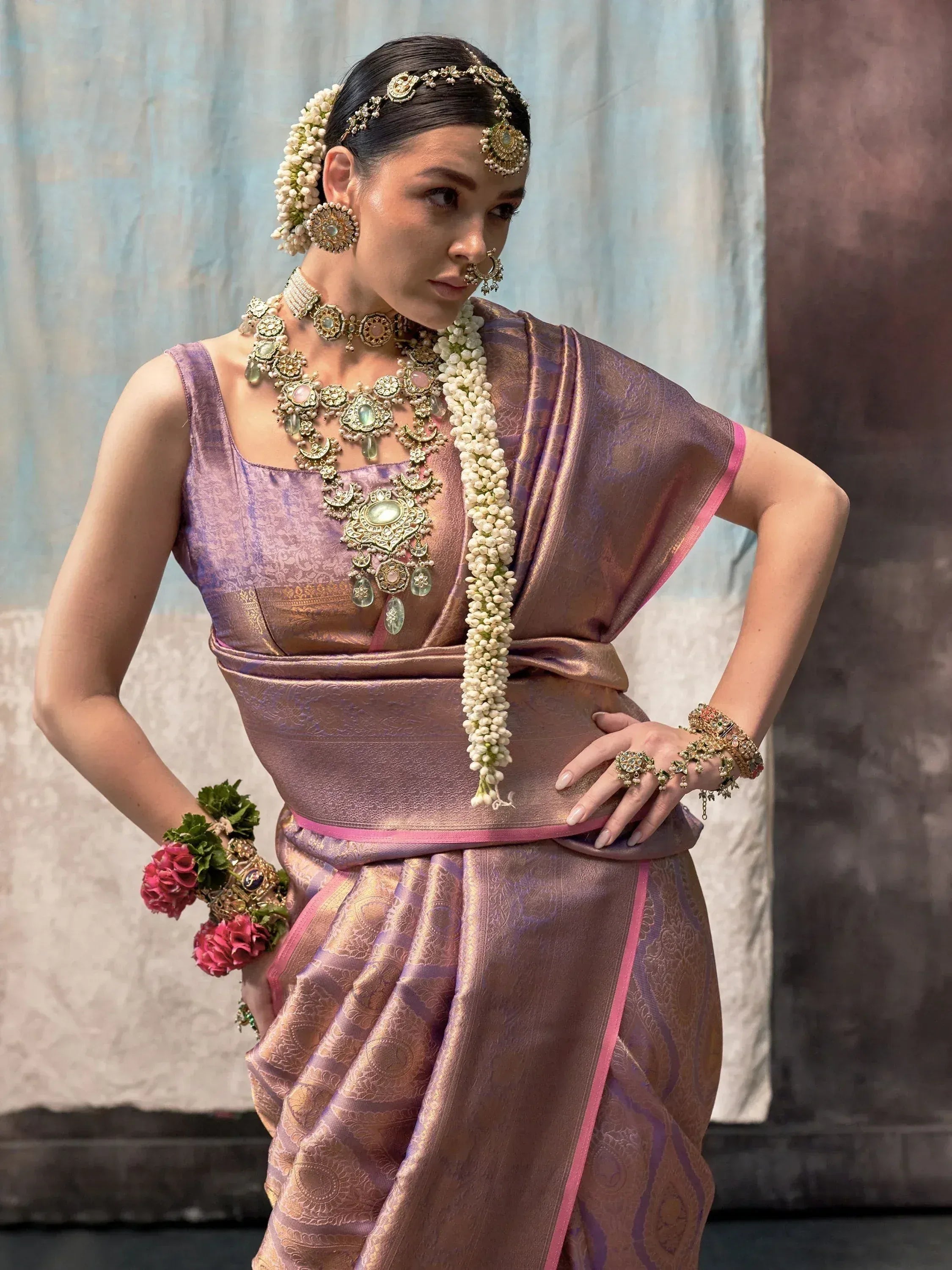Woman in purple silk saree with gold jewelry and floral accessories, traditional Indian ethnic wear