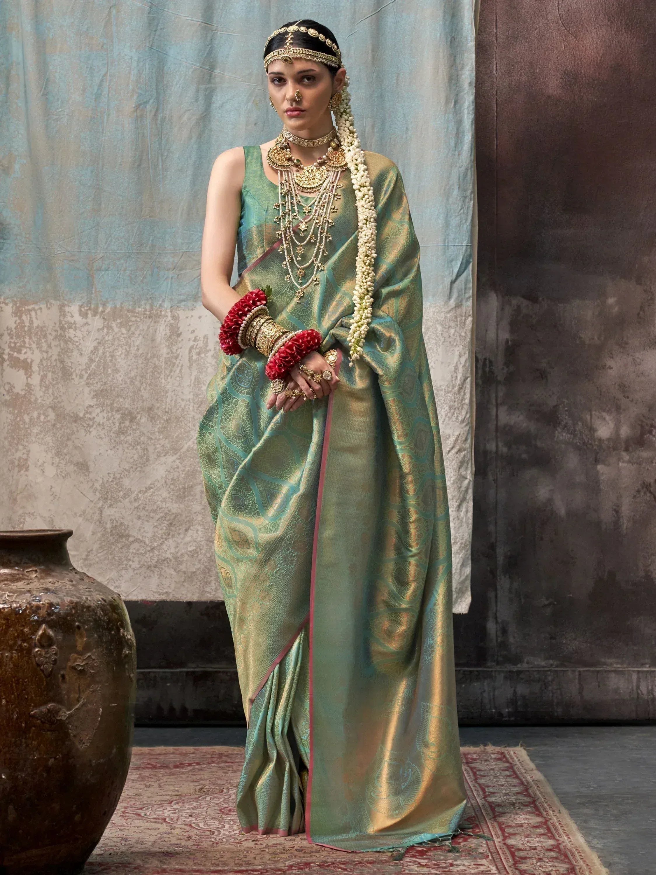 Elegant green and gold designer saree with intricate patterns, traditional jewelry, and floral accessories for Indian ethnic wear.