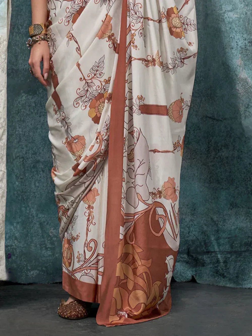 Elegant floral print saree in cream and rust, styled with traditional Indian jewelry and embellished flats.