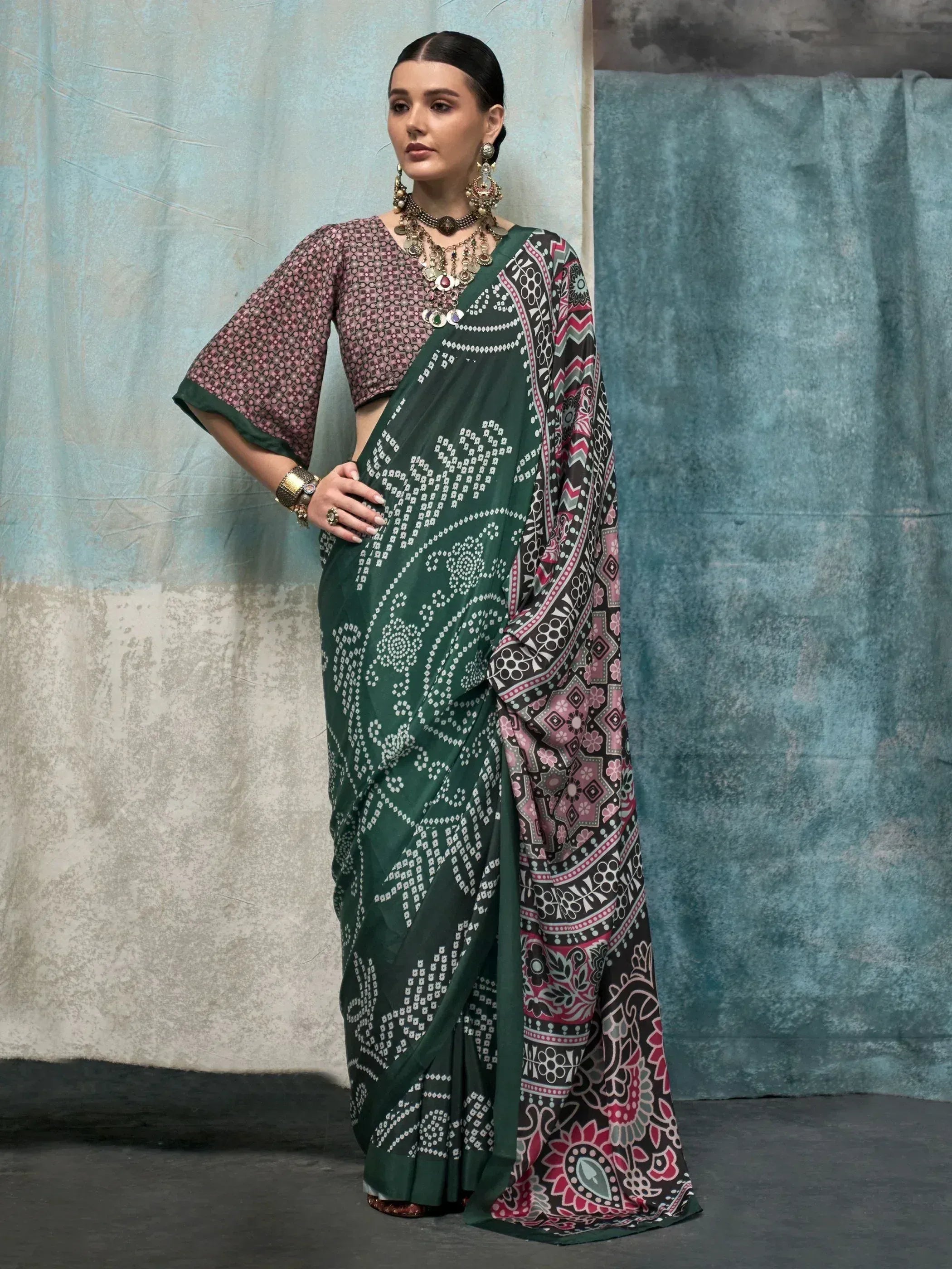 Green printed saree with pink and black border, paired with patterned blouse, ethnic jewelry