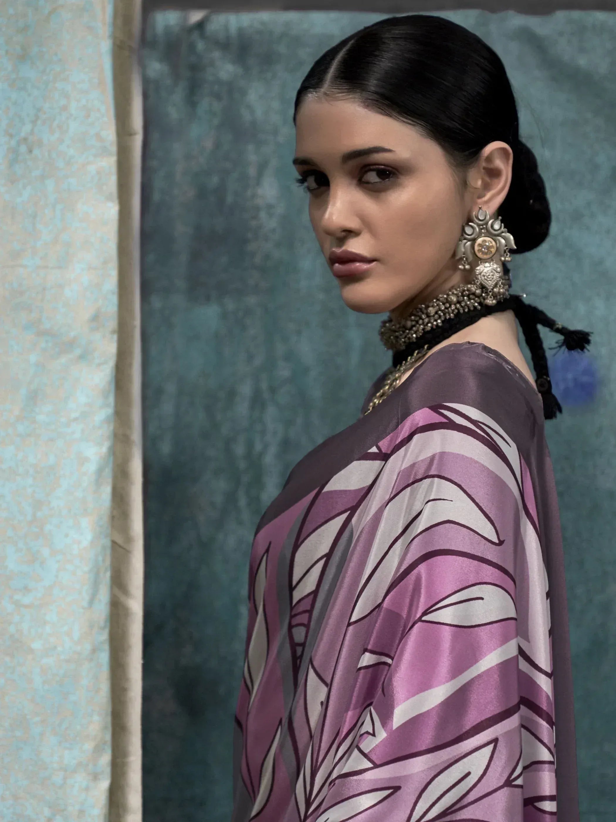 Woman in purple and white printed ethnic gown with statement jewelry, perfect for Indian occasions.