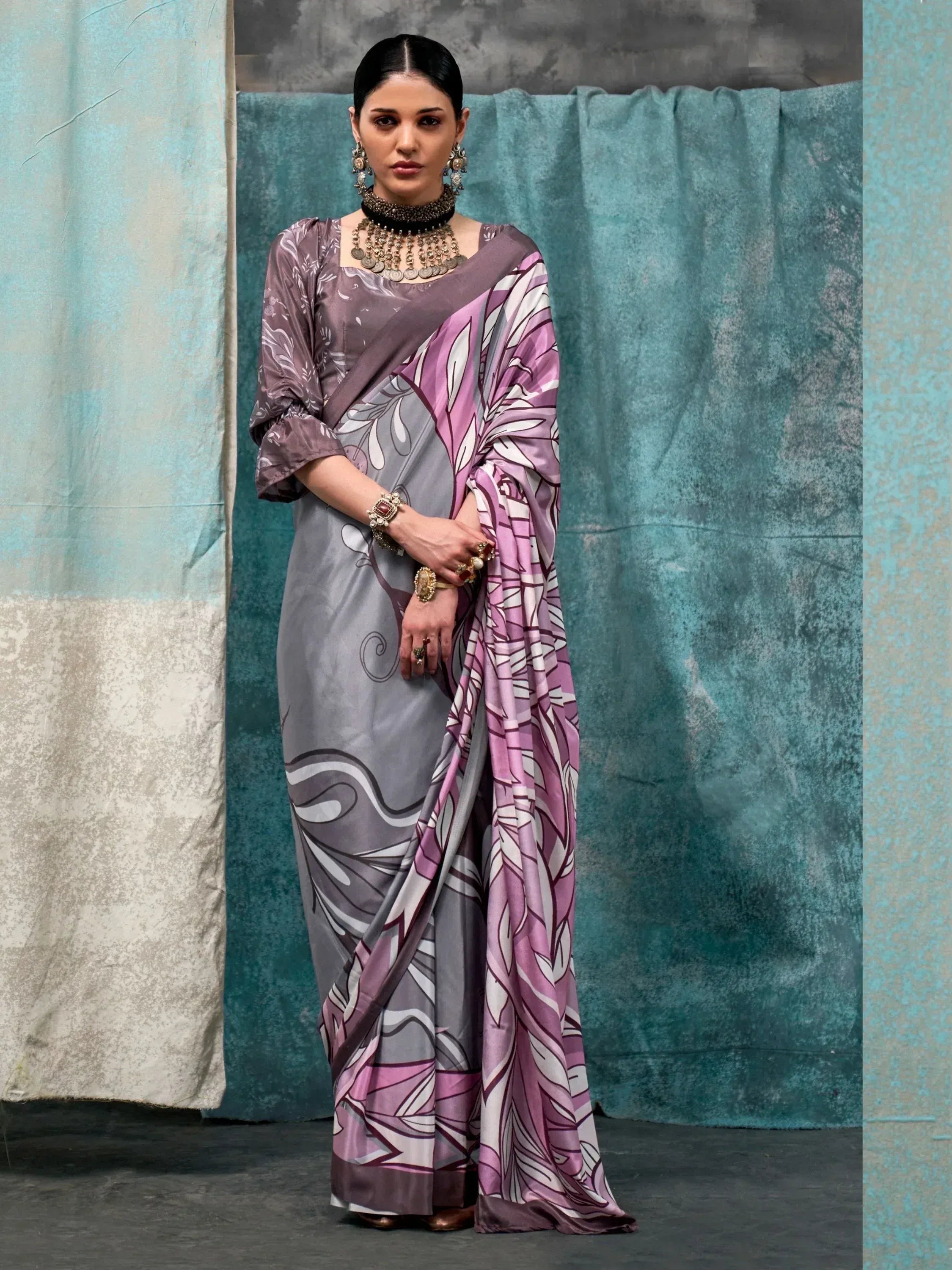 Woman in elegant grey and purple printed saree with floral design, styled with traditional jewelry for ethnic wear.