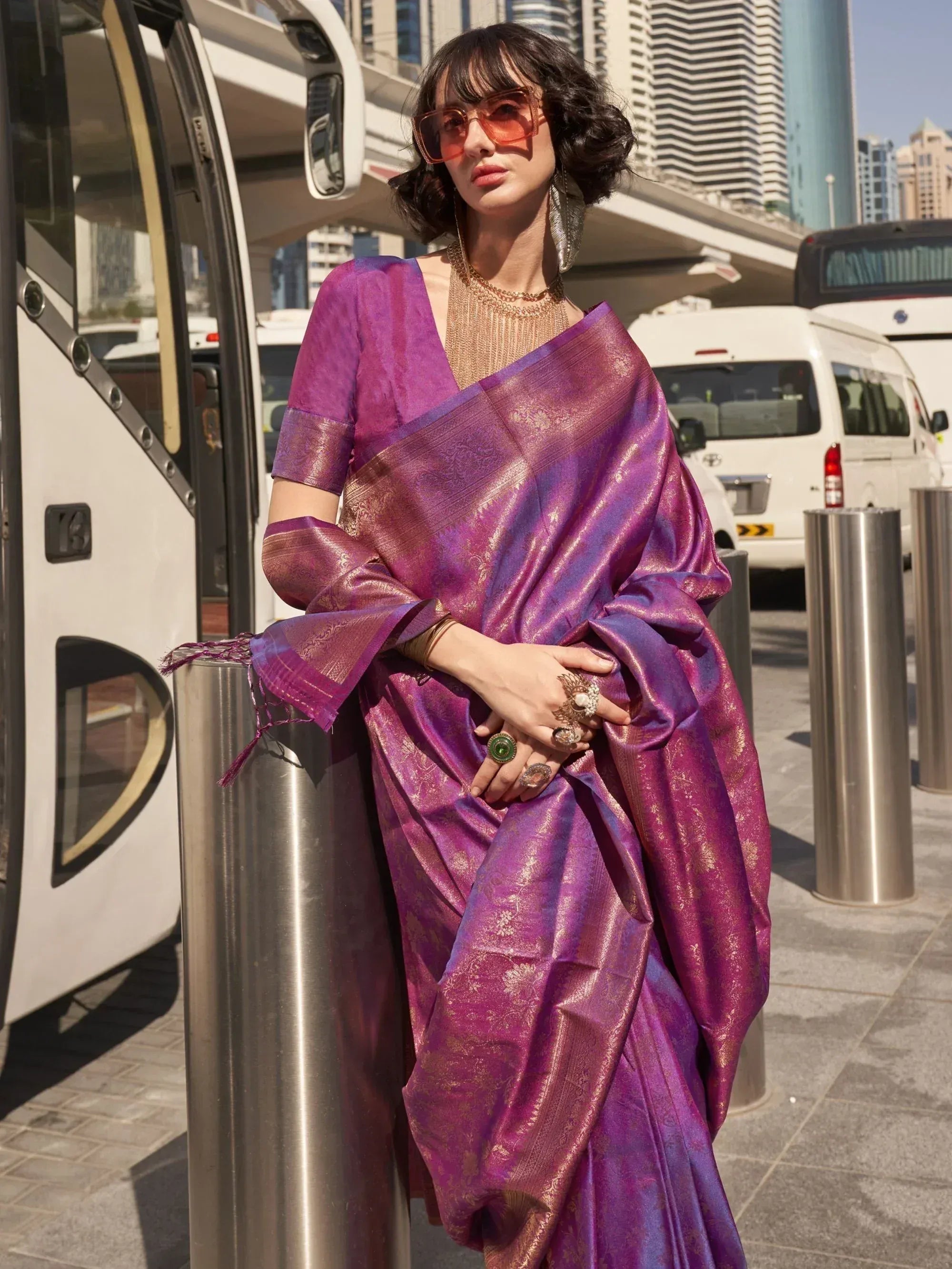 Purple designer saree with gold weave, styled with statement jewelry in urban setting