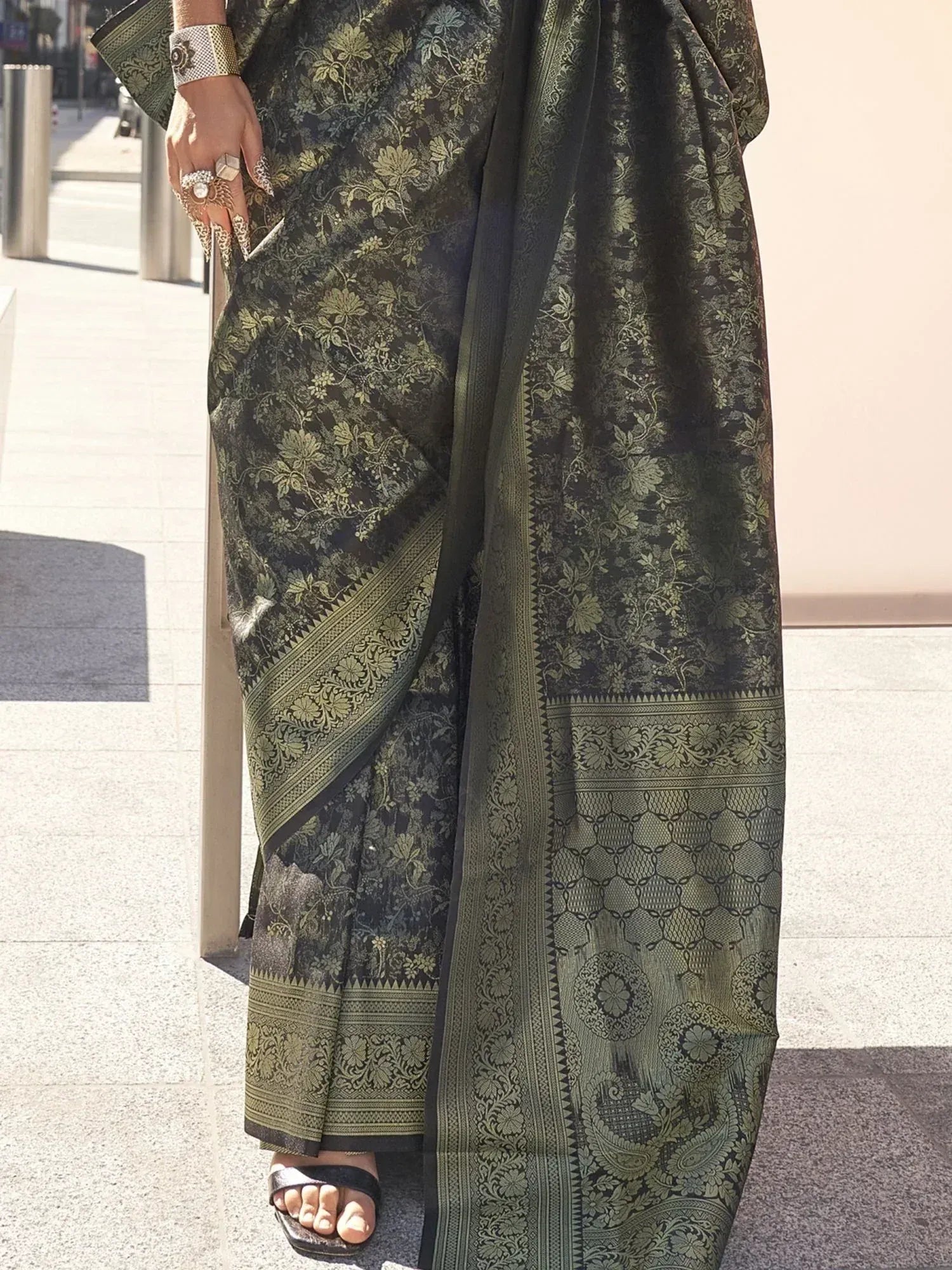 Black and olive green floral saree with intricate border, styled with traditional jewelry for ethnic wear.