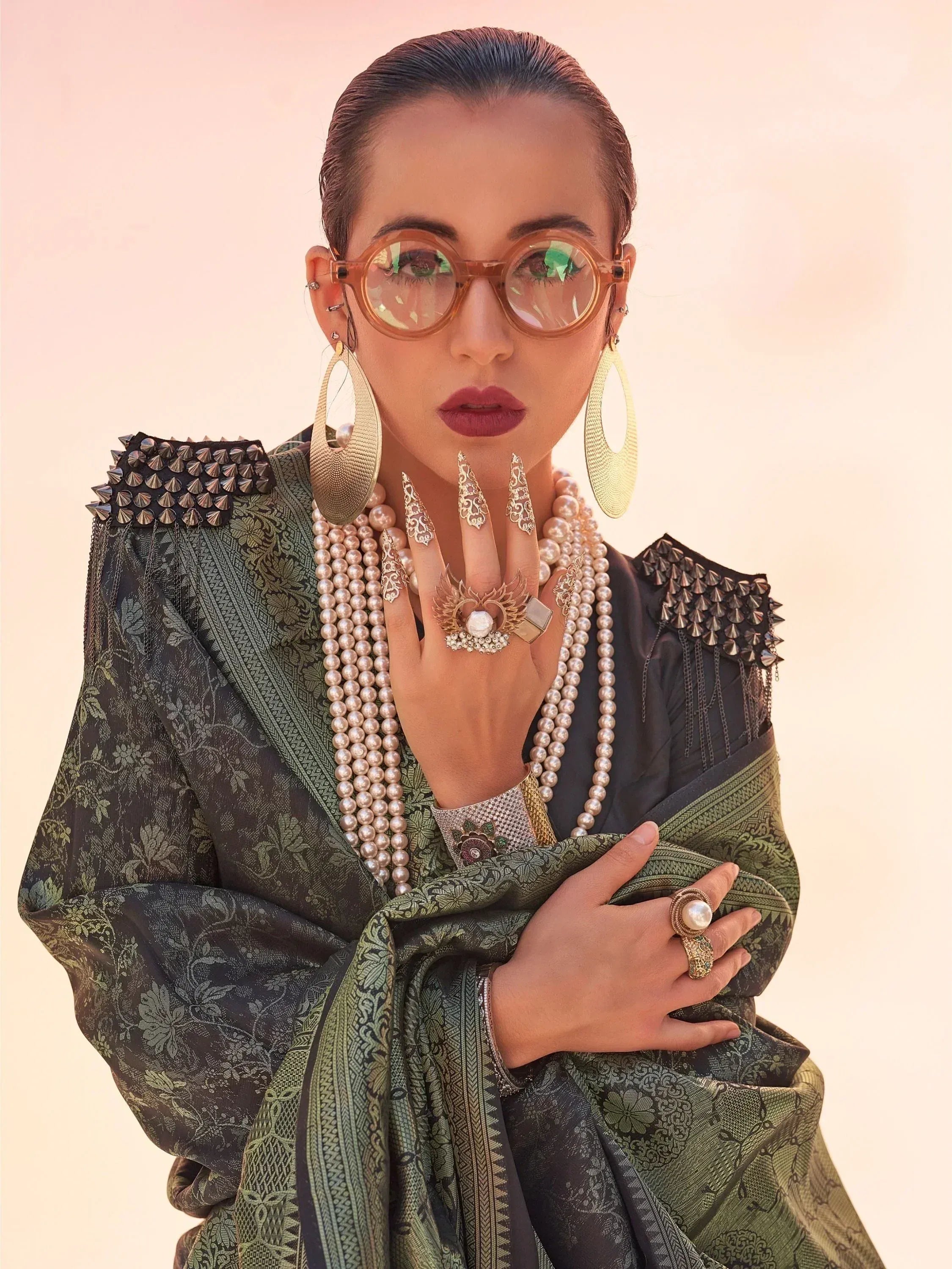 Stylish woman in ethnic green saree with pearl jewelry and statement glasses