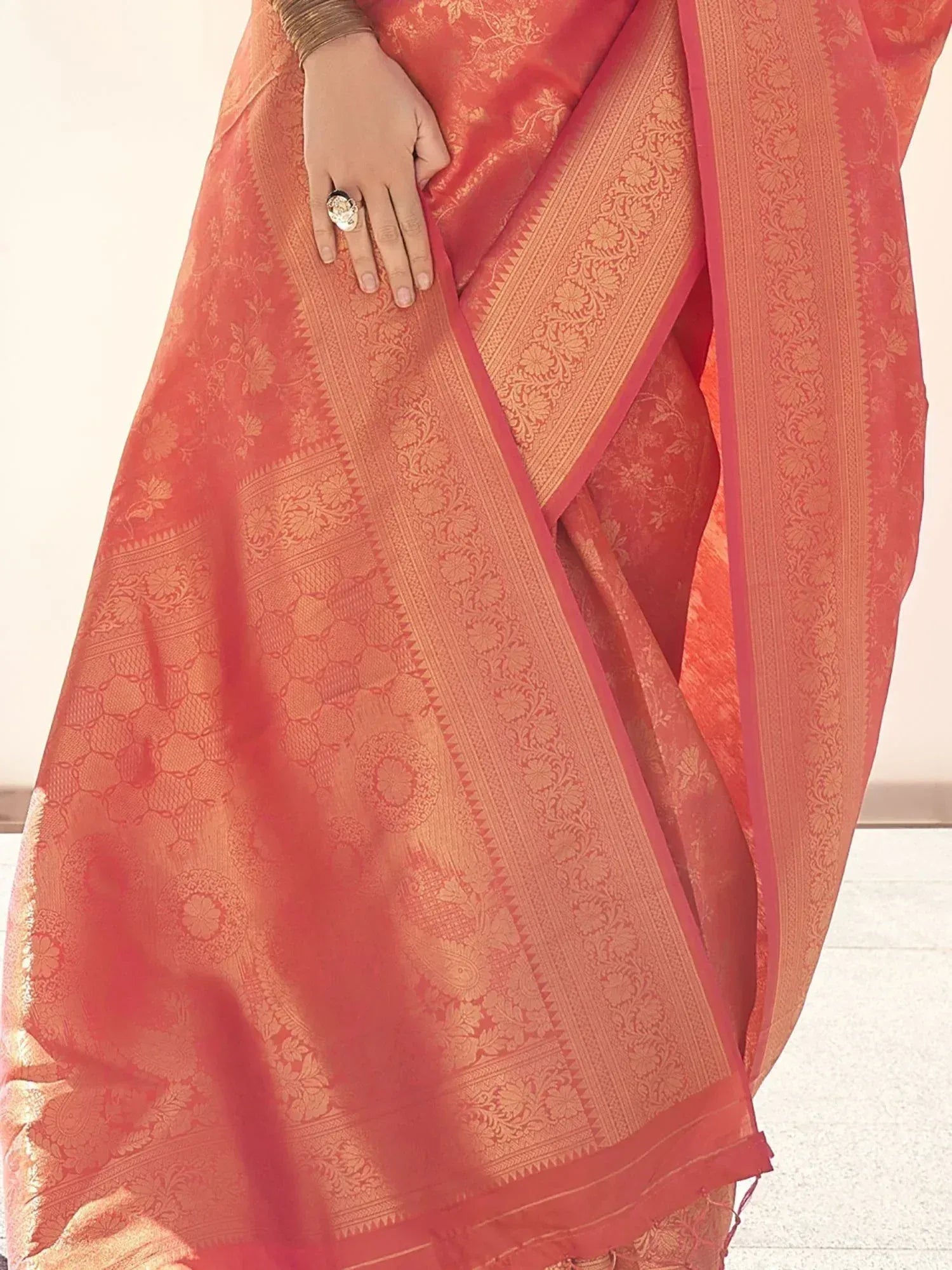 Coral designer saree with gold floral motifs and intricate border, perfect for ethnic occasions