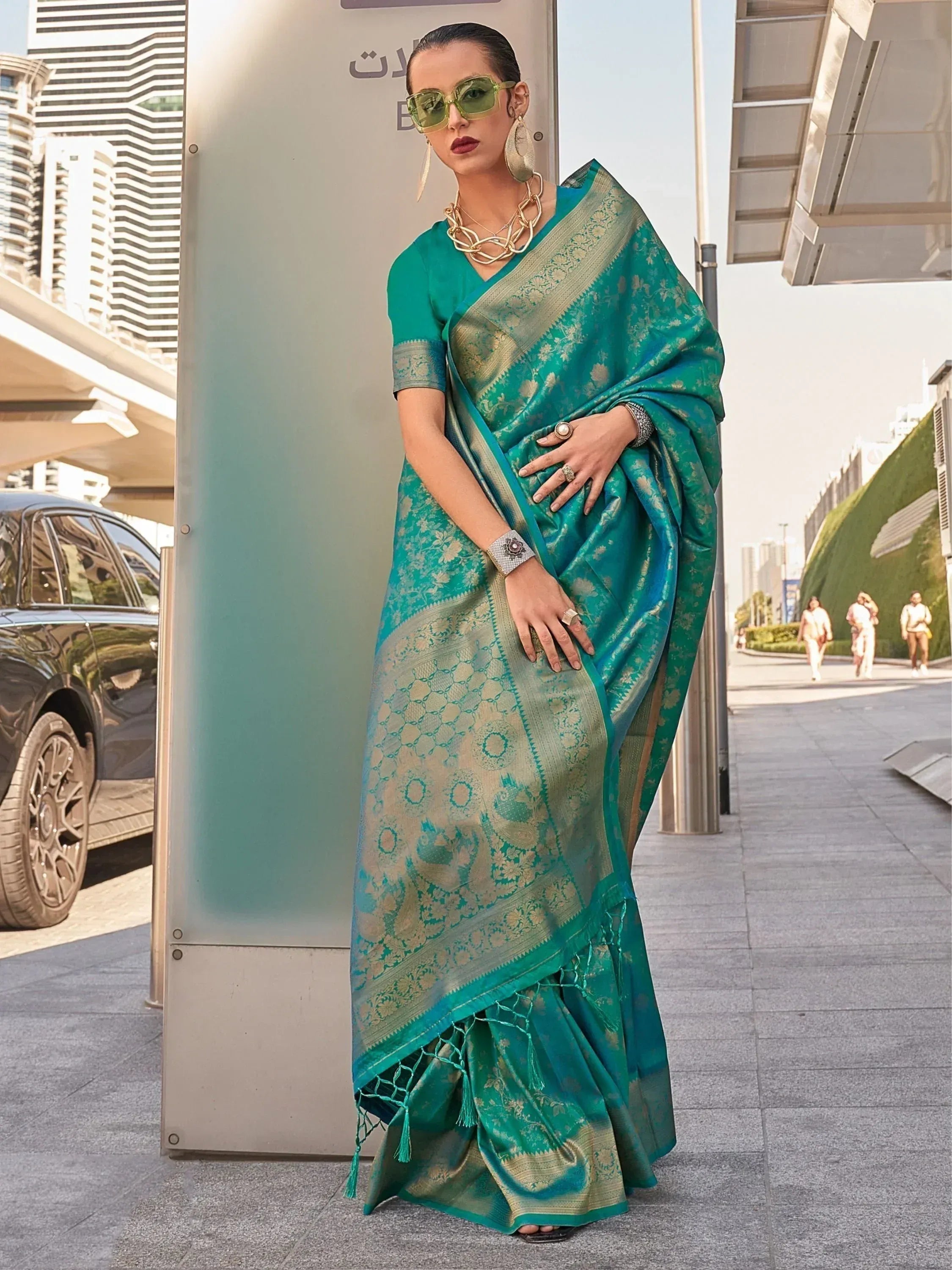 Teal designer saree with gold floral motifs and tassels, styled for modern ethnic wear
