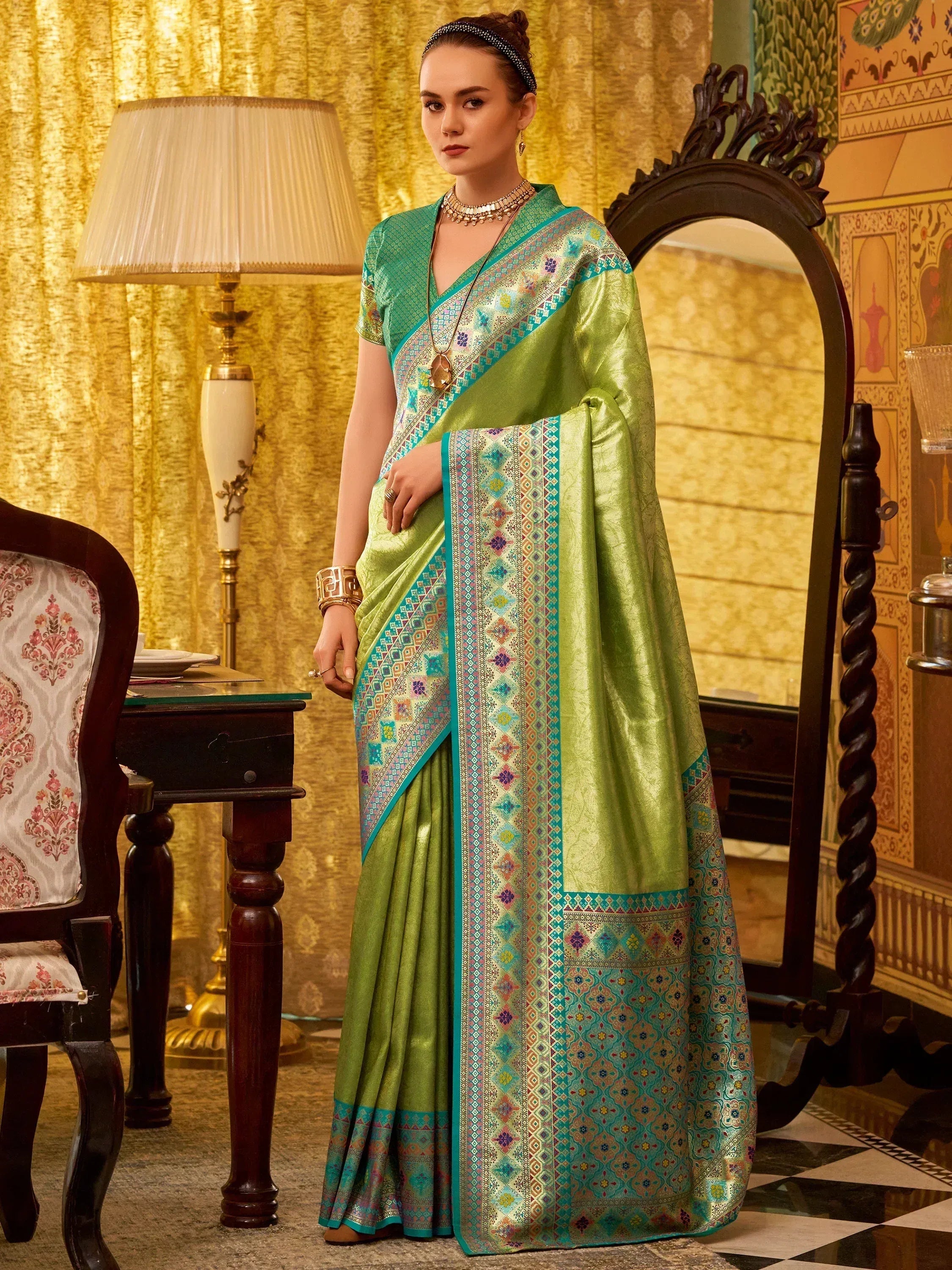 Green and teal designer saree with intricate geometric patterns and ethnic jewelry