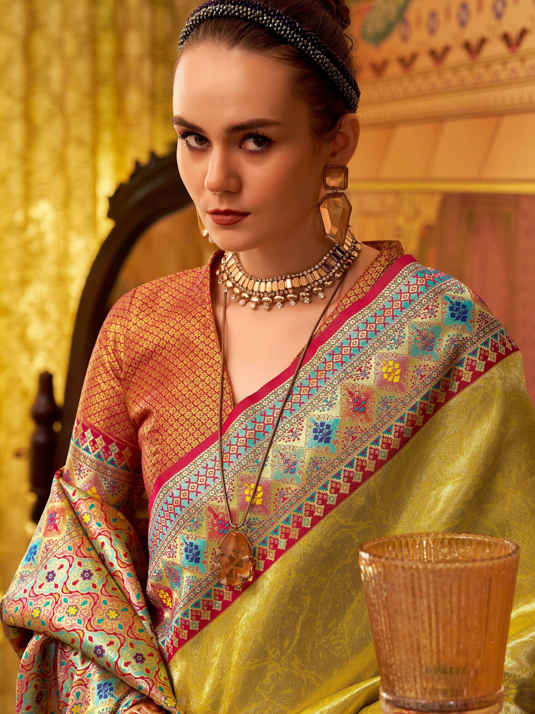 Elegant woman in vibrant Indian saree with intricate floral patterns and gold accents, styled with bold jewelry.
