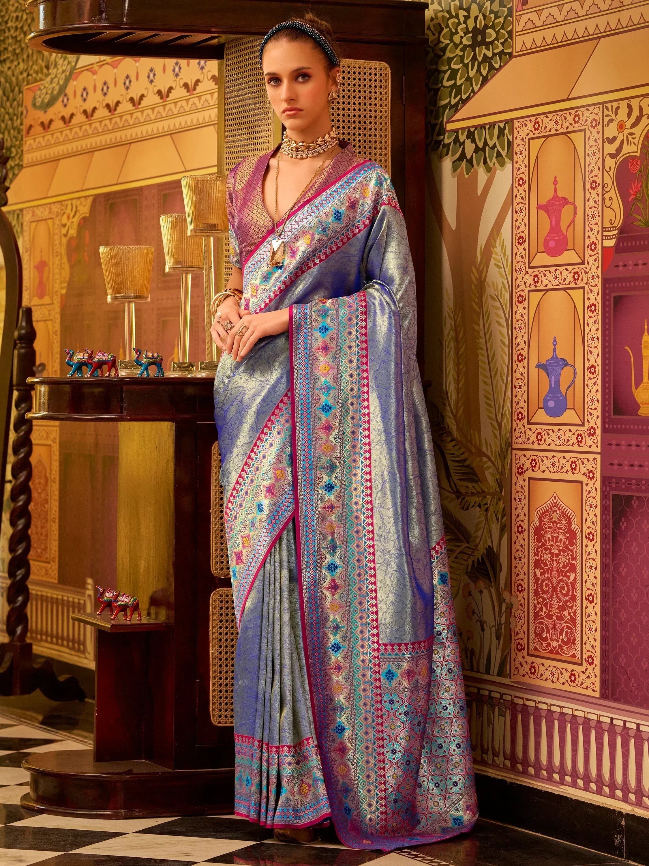 Elegant blue and pink ethnic saree with intricate geometric patterns, styled with traditional jewelry.