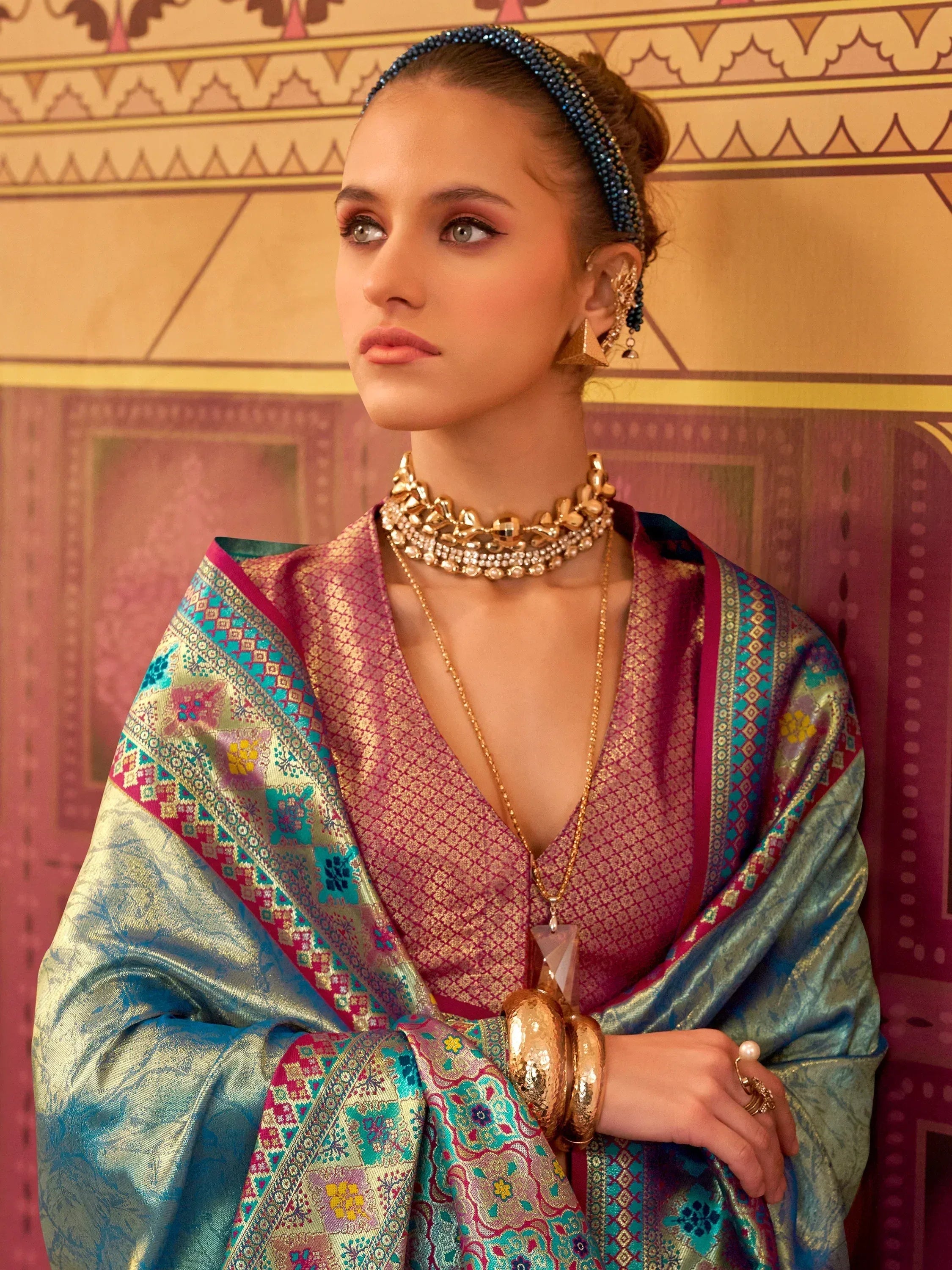 Elegant woman in vibrant Indian ethnic saree with intricate patterns and gold jewelry