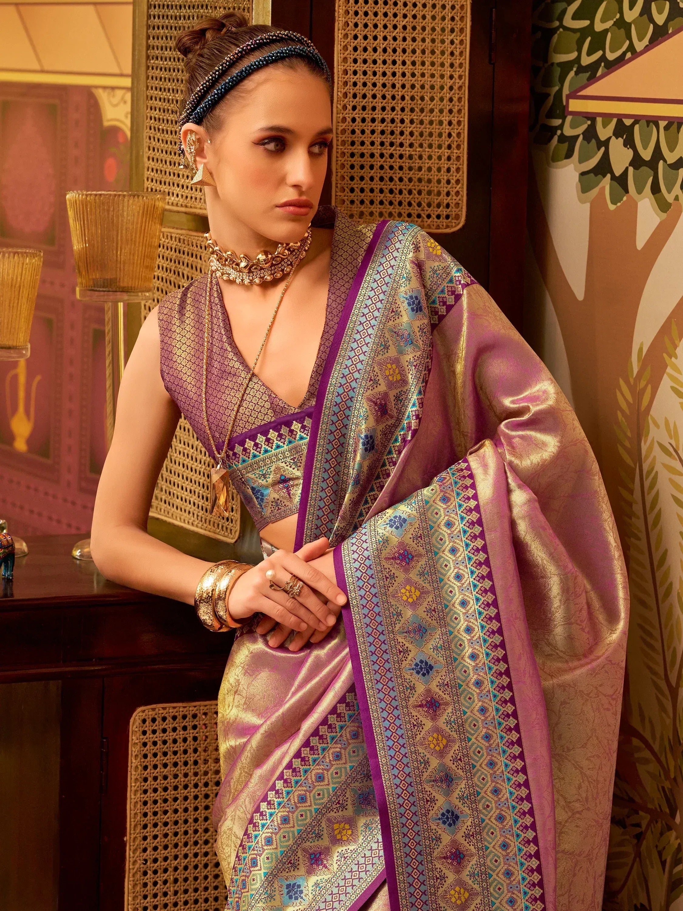 Elegant purple and gold saree with intricate patterns, paired with traditional jewelry for festive occasions.