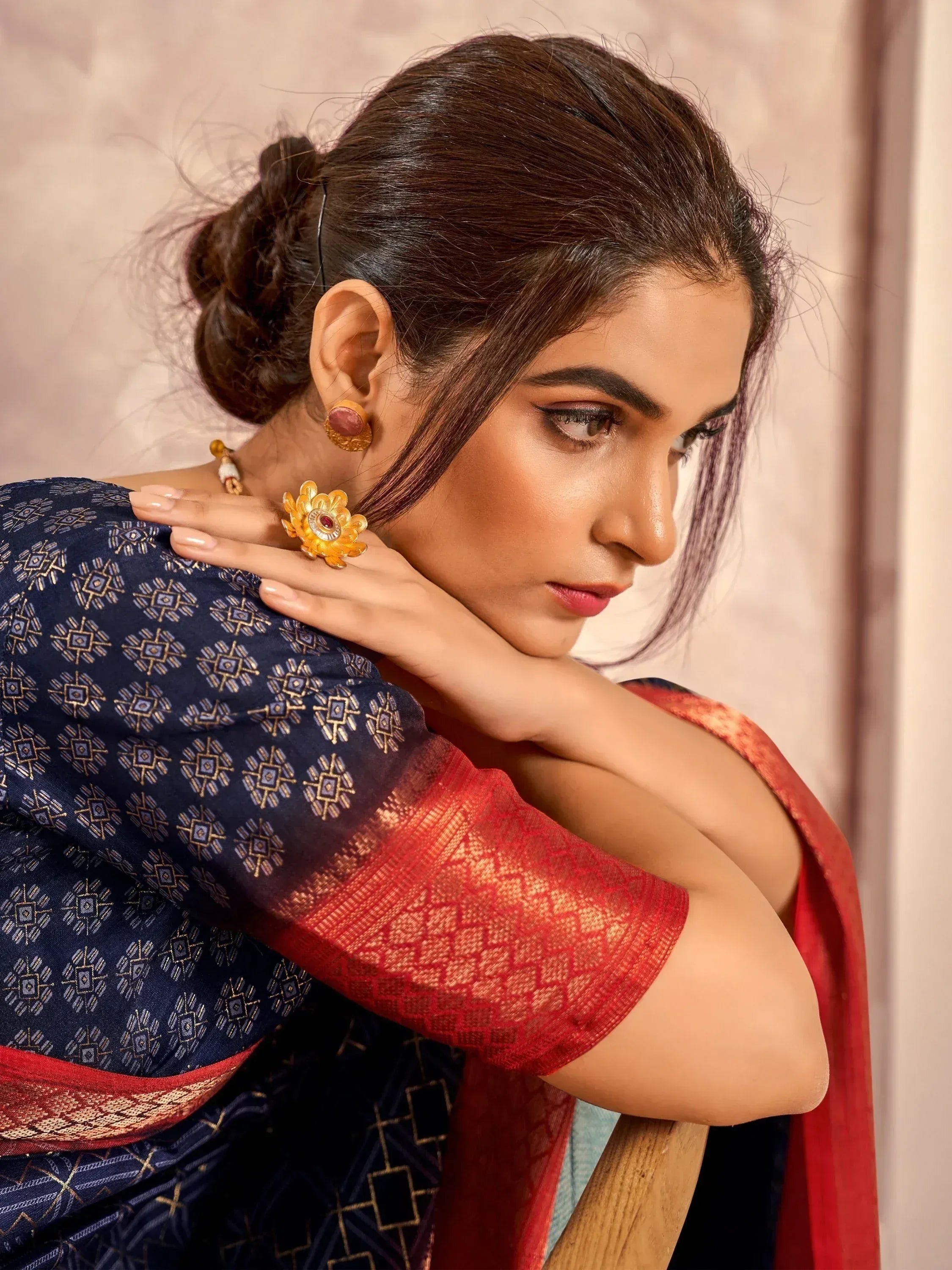 Woman in elegant navy blue and red ethnic saree with gold geometric print, styled with traditional jewelry