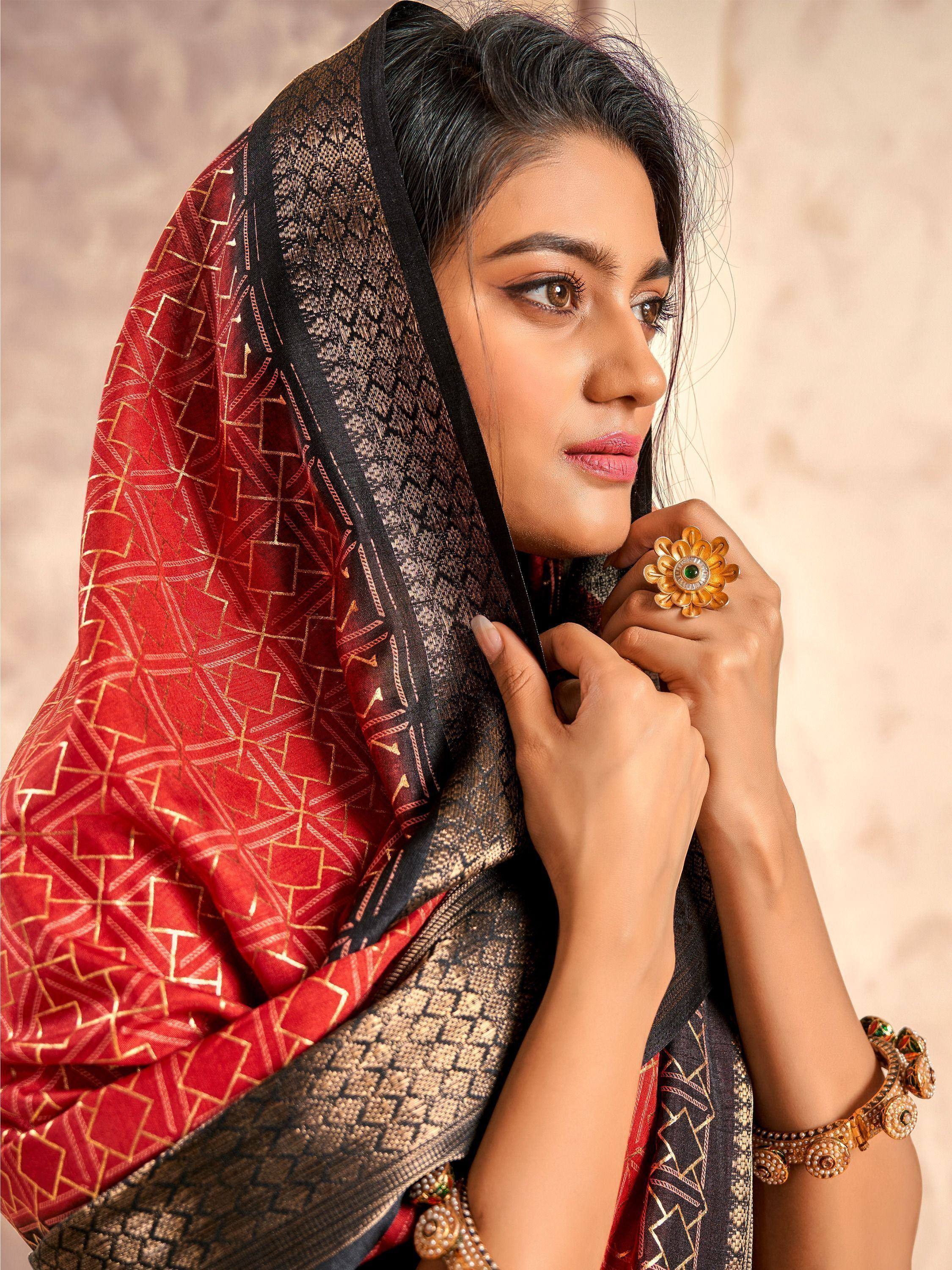 Woman in red and black ethnic saree with gold geometric print, traditional jewelry, and elegant pose