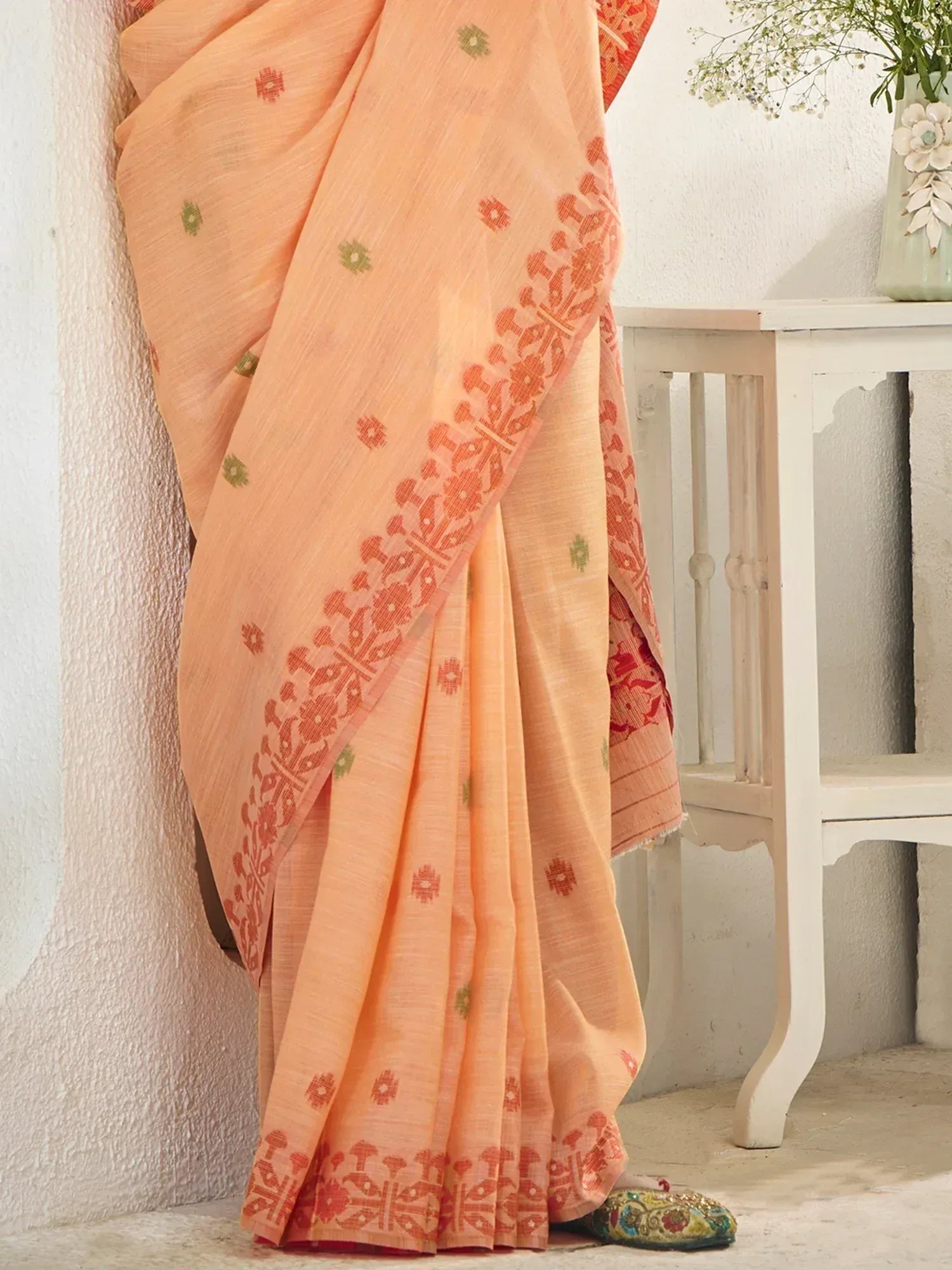 Peach ethnic saree with red and green floral motifs, perfect for Indian occasions