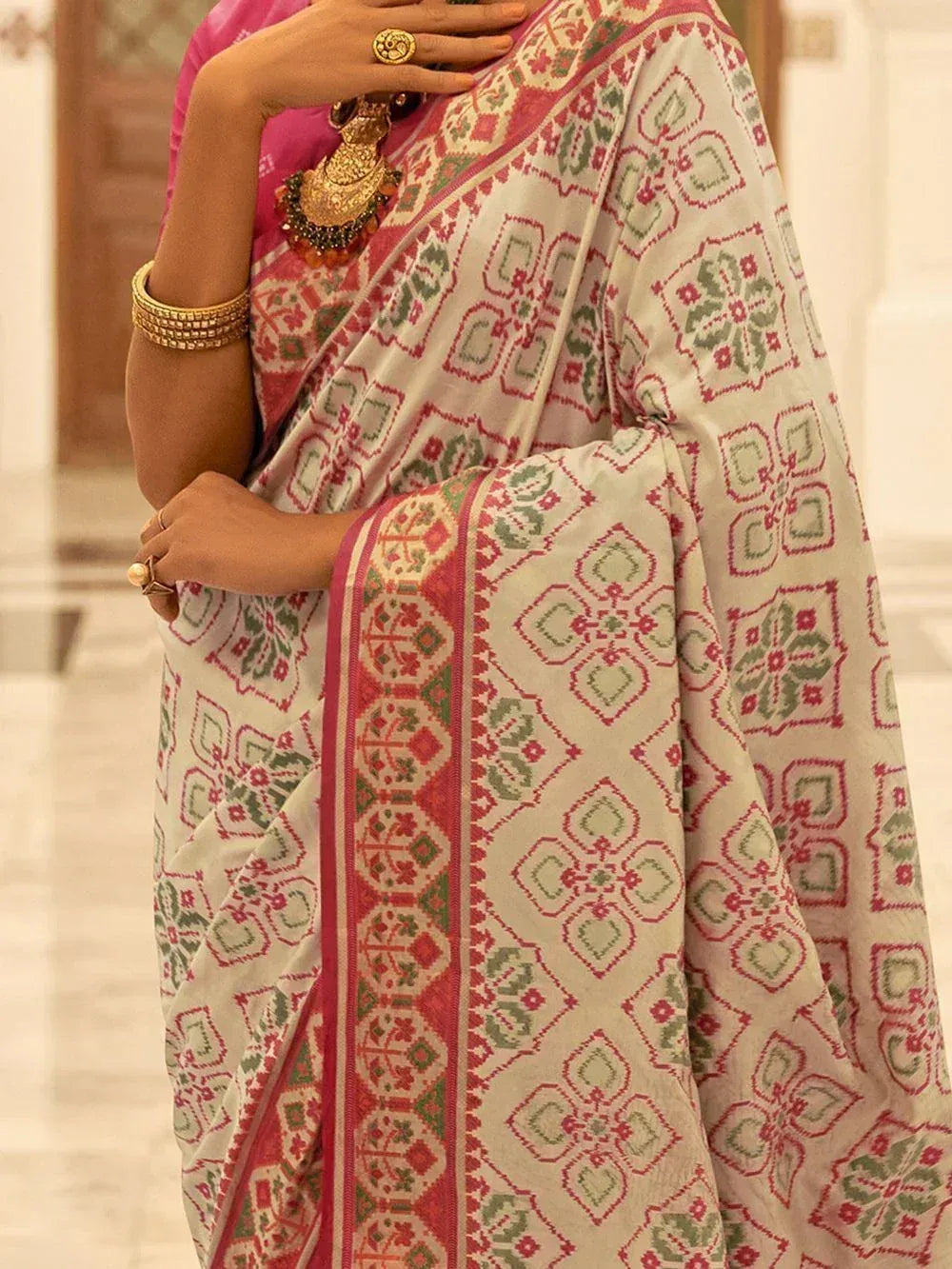 Woman in elegant ethnic saree with red green geometric print, gold jewelry, and pink blouse