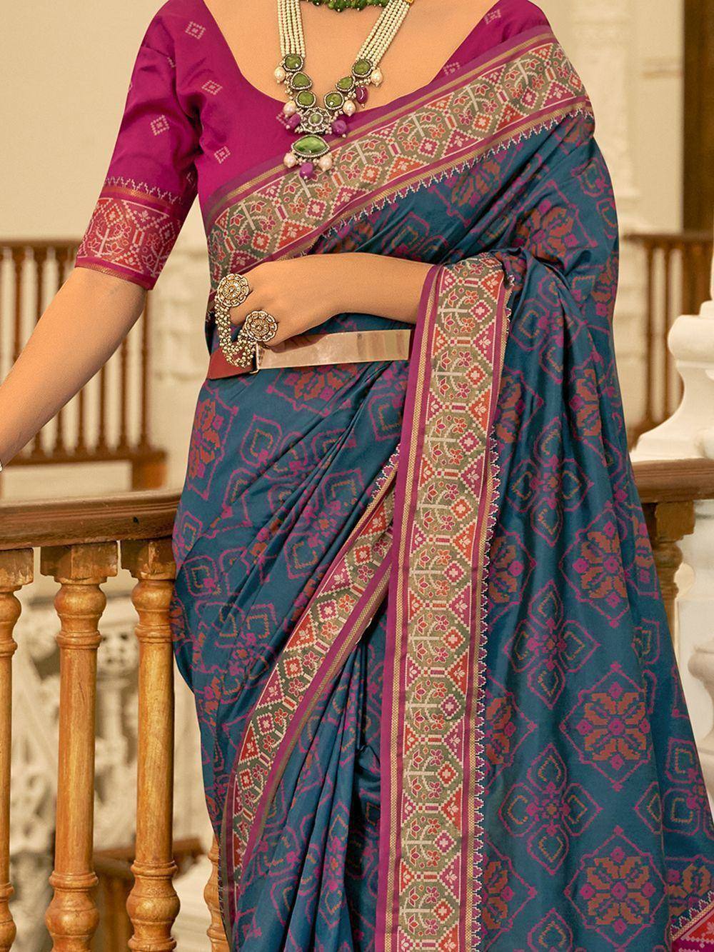 Teal and magenta ethnic saree with intricate geometric border, paired with matching blouse and statement jewelry