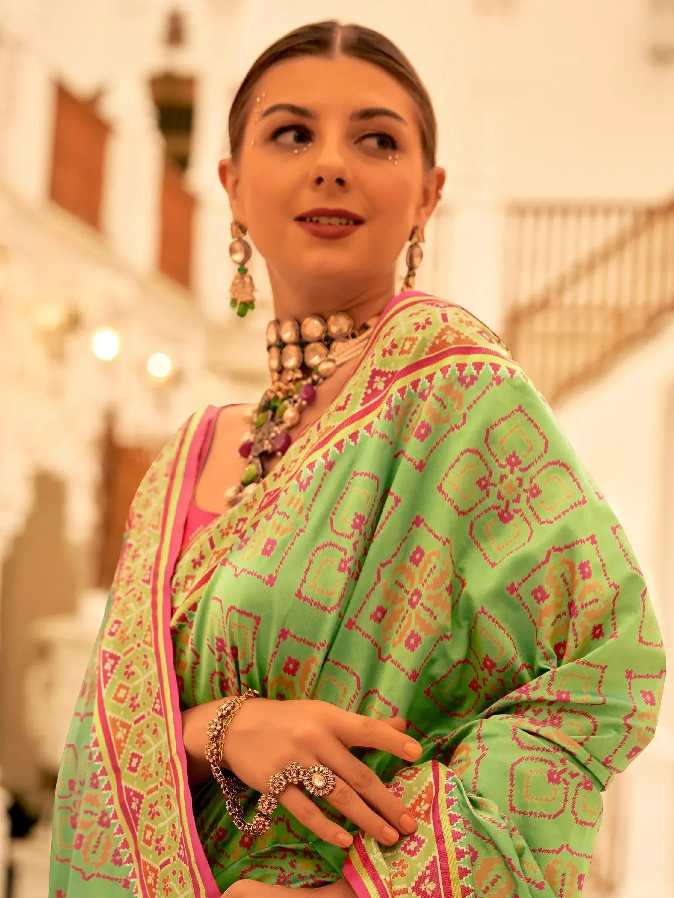 Woman in vibrant green and pink printed saree with traditional jewelry, showcasing Indian ethnic wear