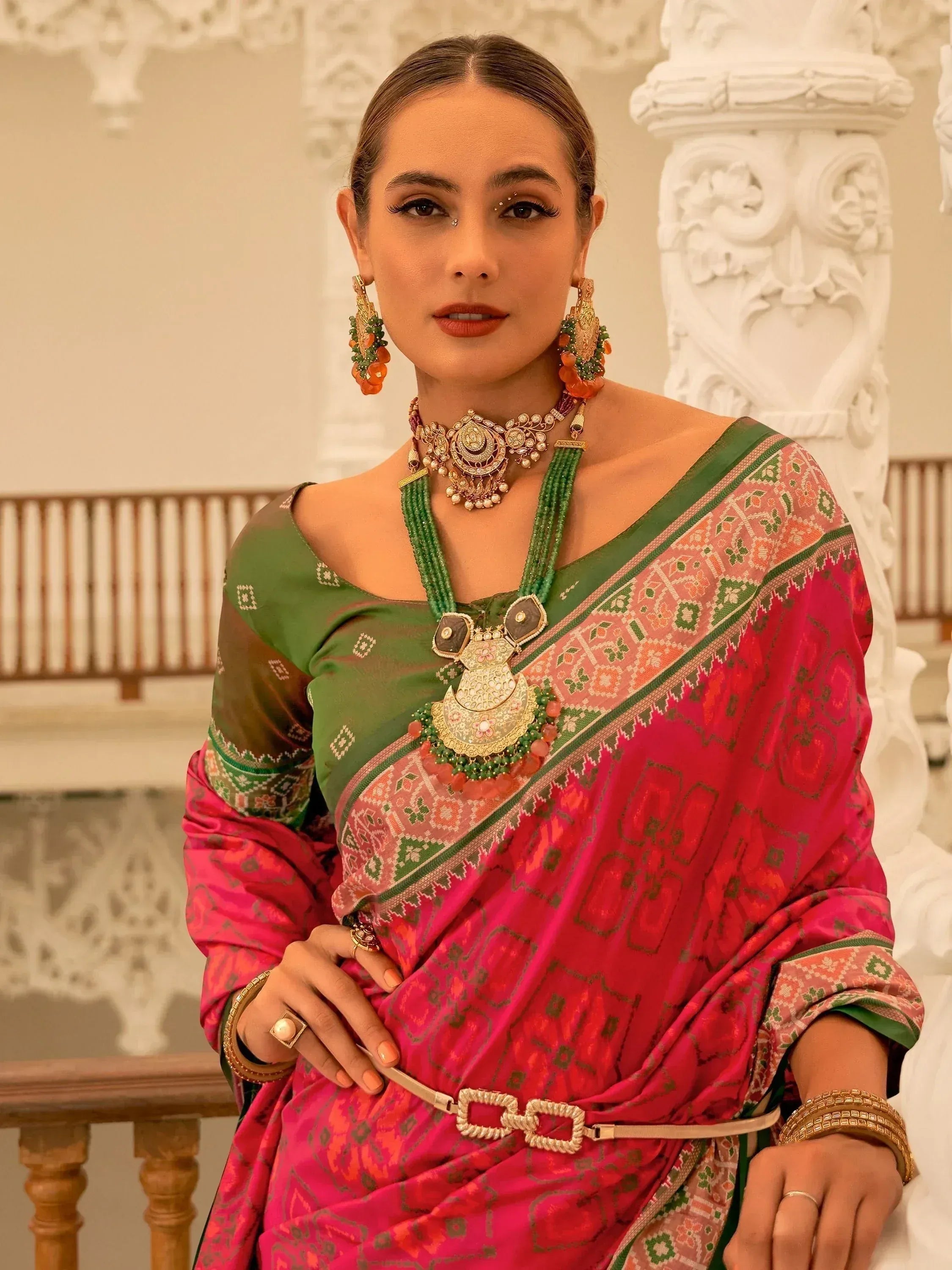 Woman in vibrant pink and green ethnic saree with intricate jewelry, perfect for Indian festive occasions.