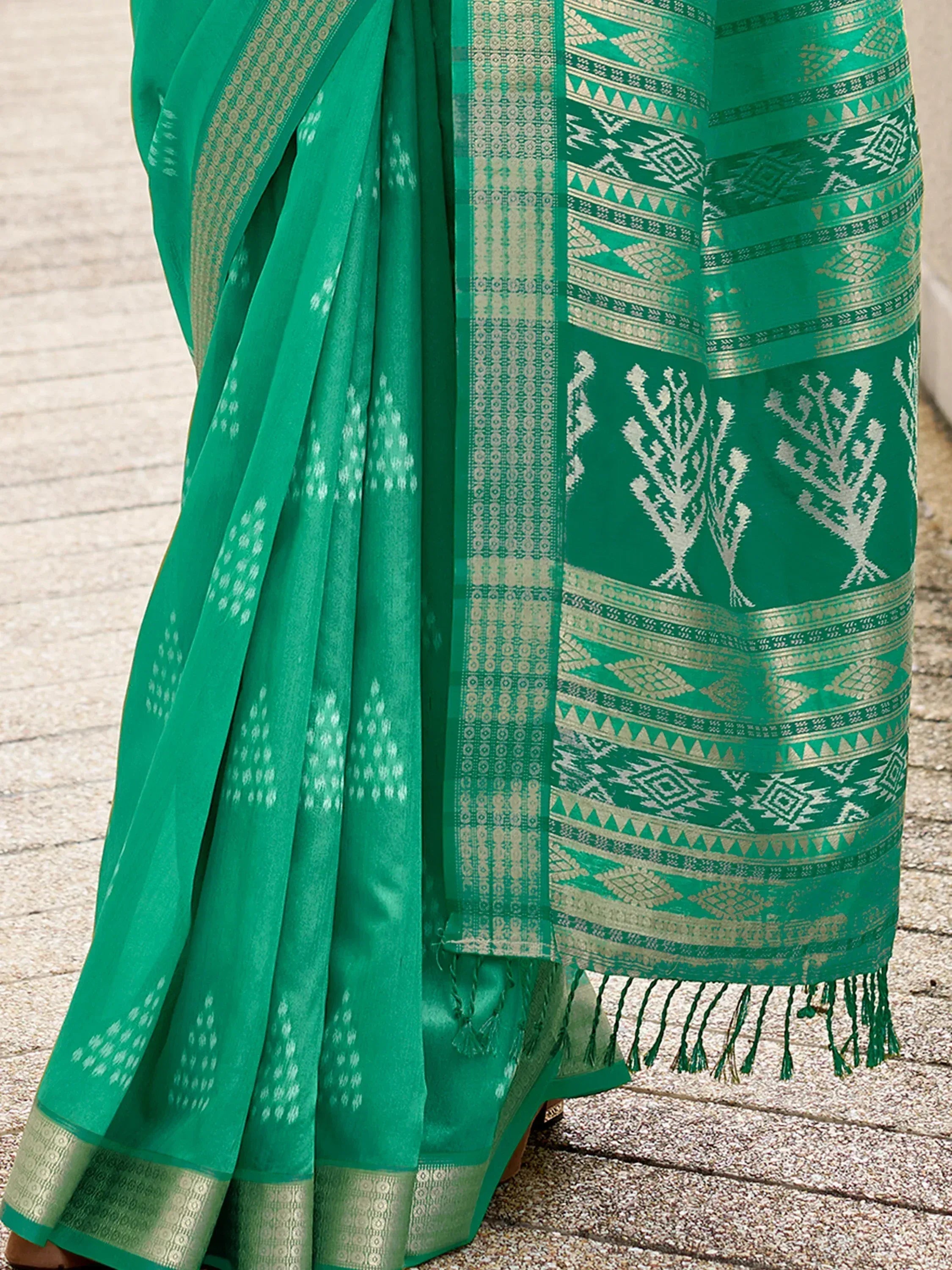 Emerald green ethnic saree with intricate white and gold geometric patterns and tassels, ideal for traditional occasions.