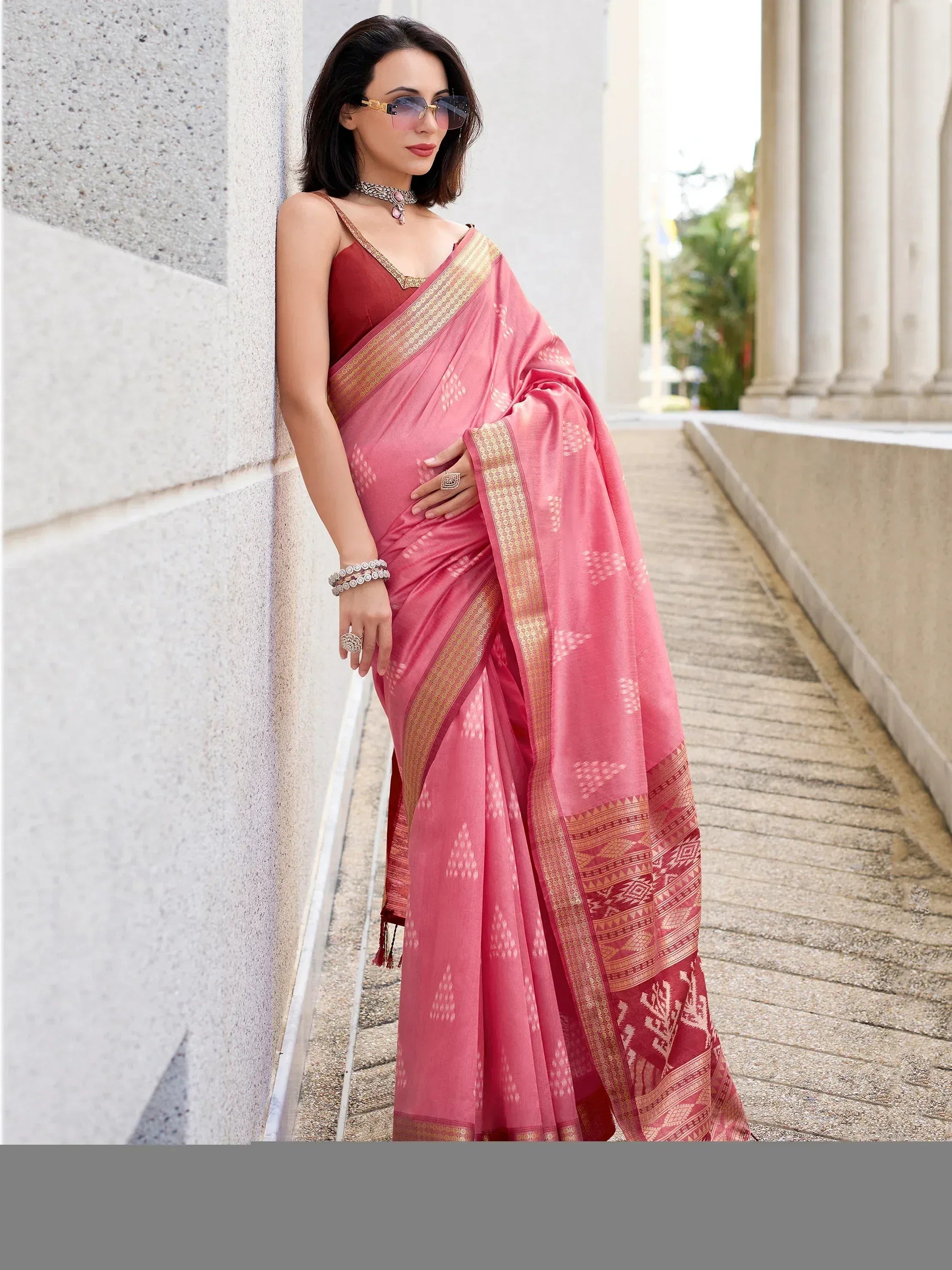 Pink designer saree with gold border and ethnic print, paired with red blouse, perfect for Indian occasions.