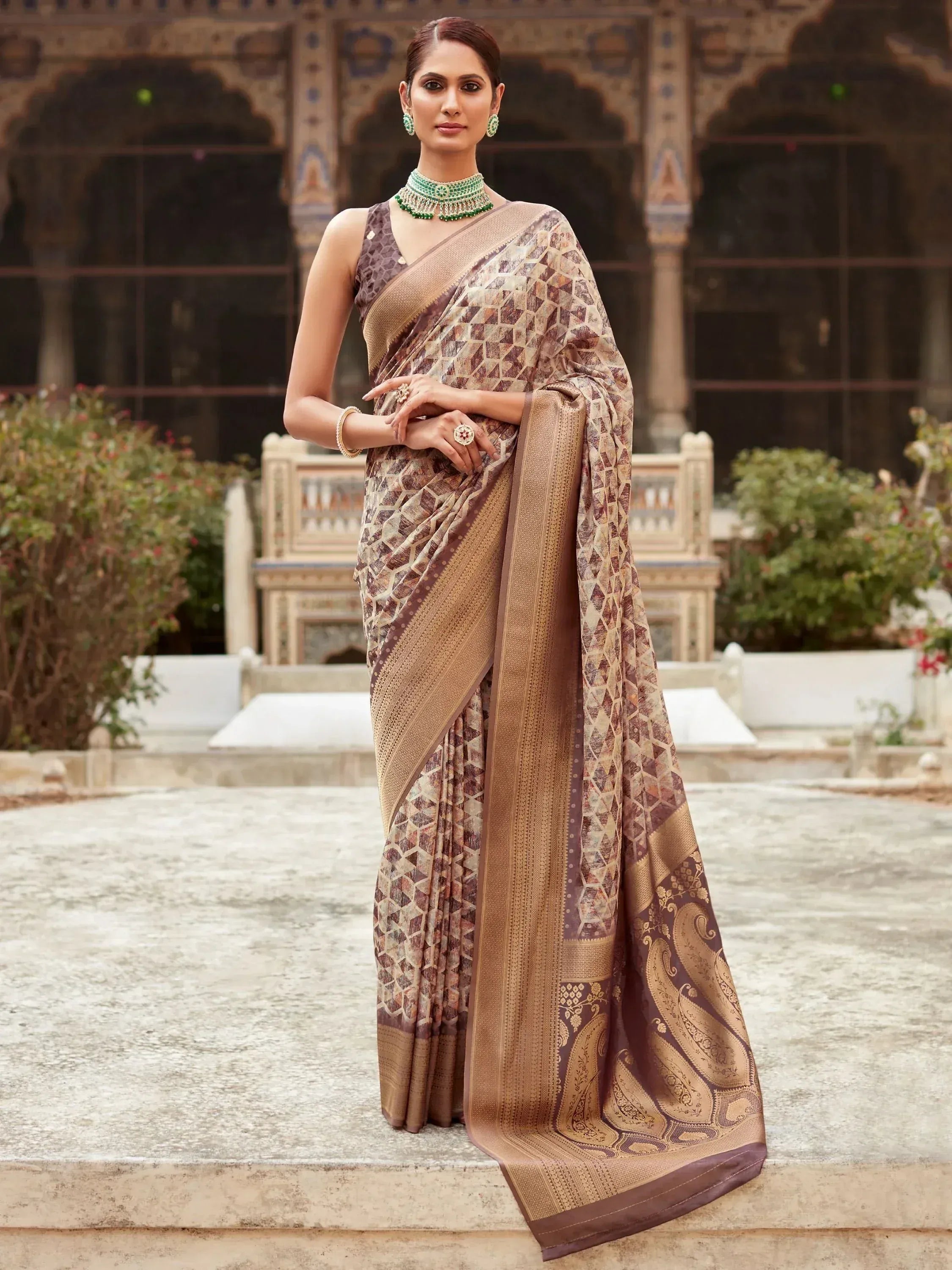 Elegant brown geometric print saree with gold border, styled with green jewelry for Indian ethnic wear