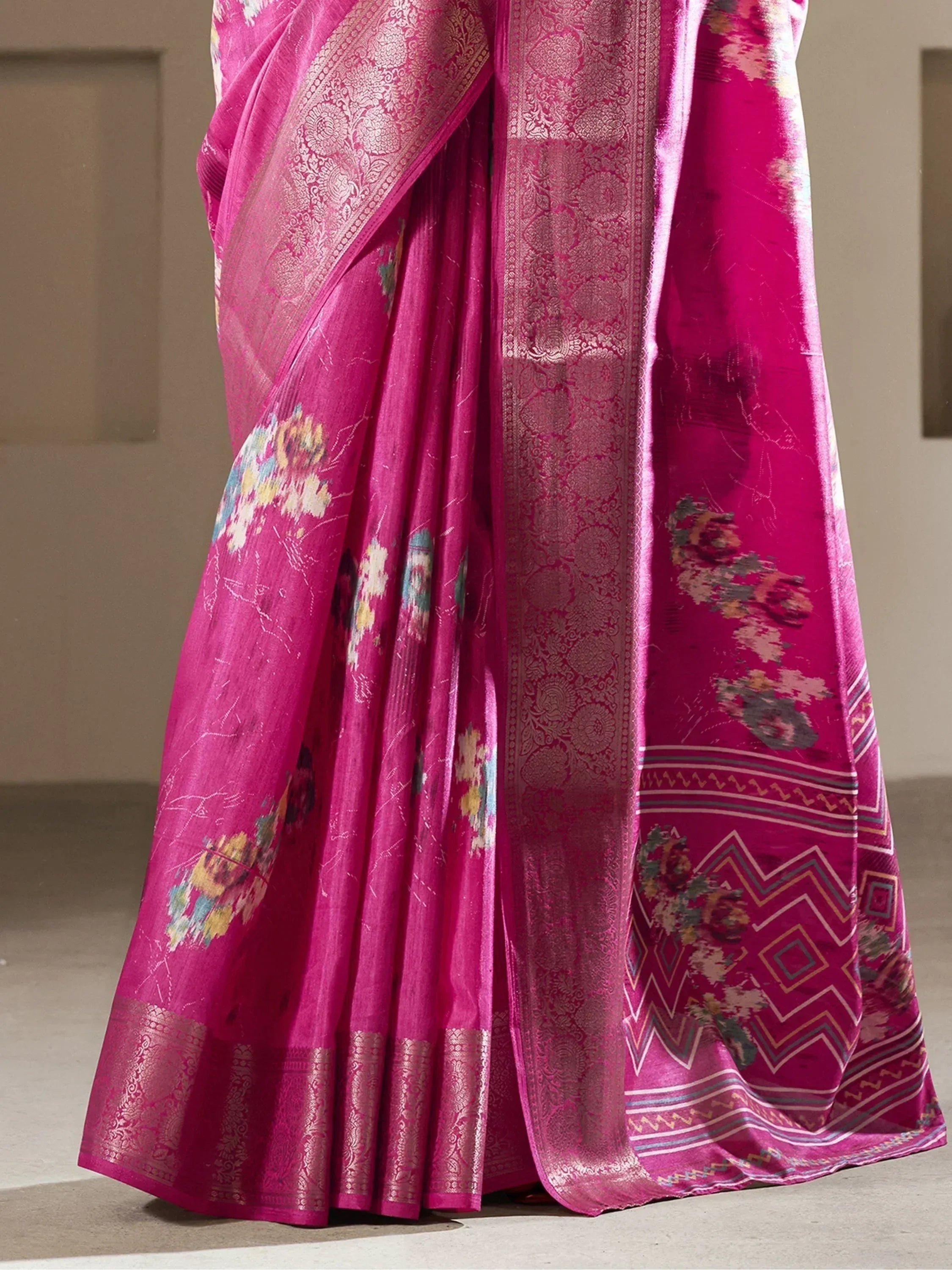 Vibrant pink floral saree with intricate gold border and geometric pallu, ideal for Indian ethnic wear occasions.