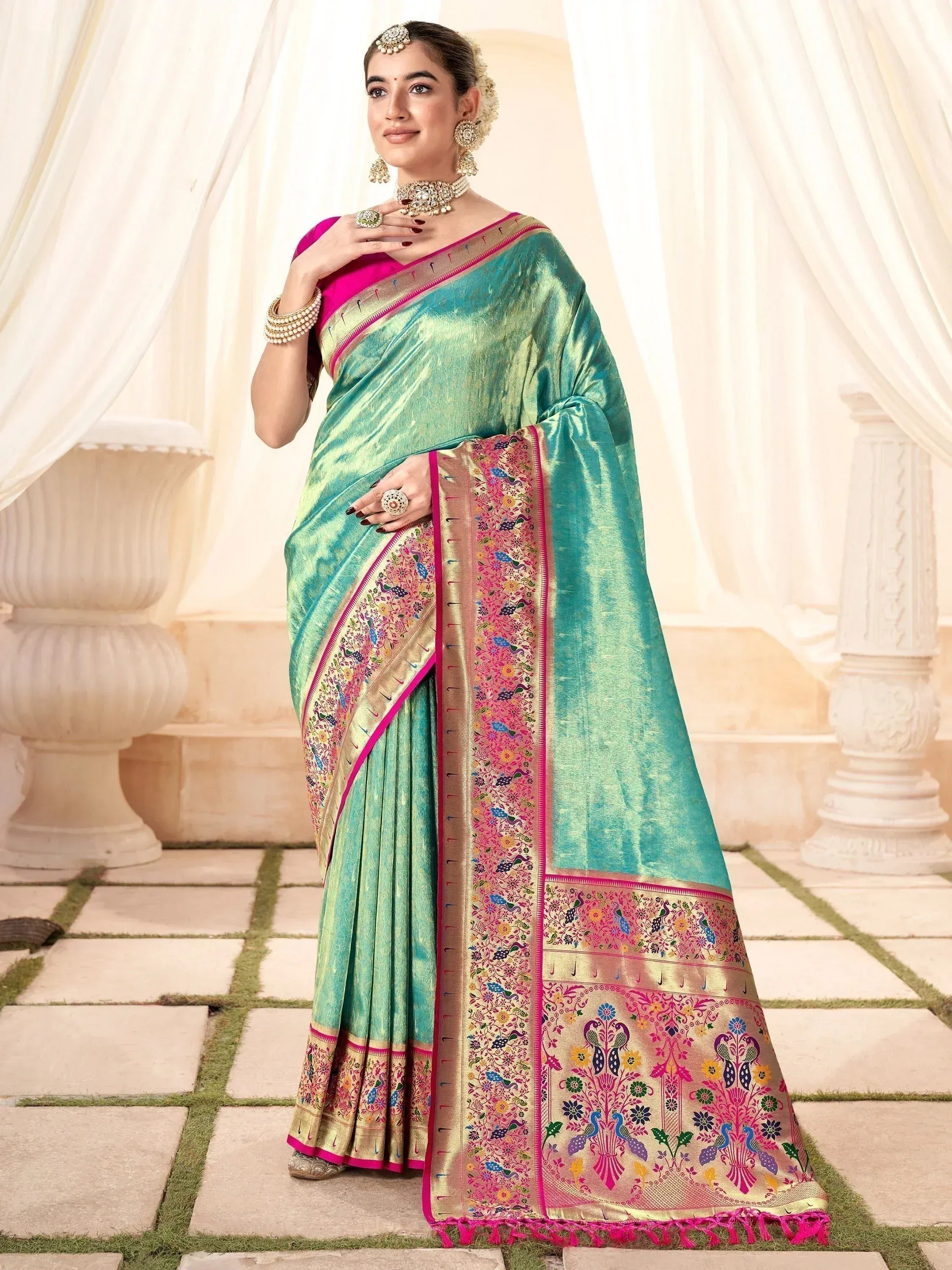 Teal silk saree with pink border and peacock embroidery, styled with traditional jewelry for Indian ethnic wear