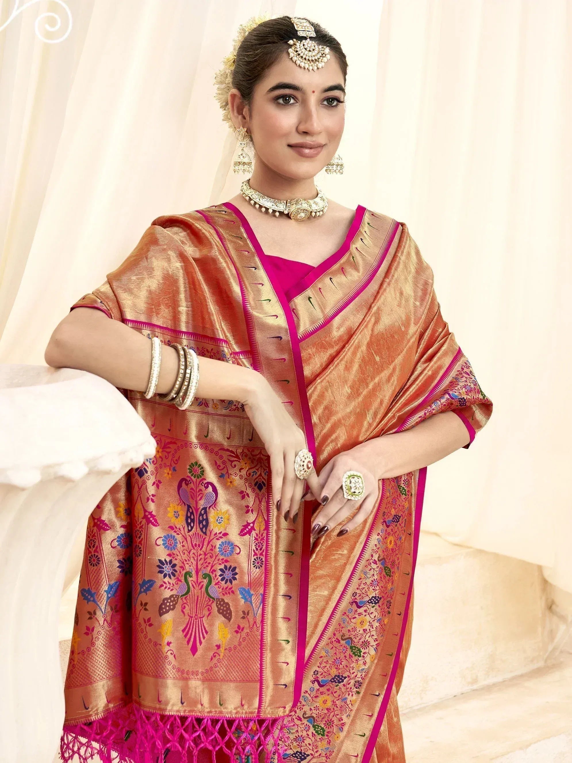 Woman in golden saree with peacock embroidery and pink border, traditional Indian ethnic wear