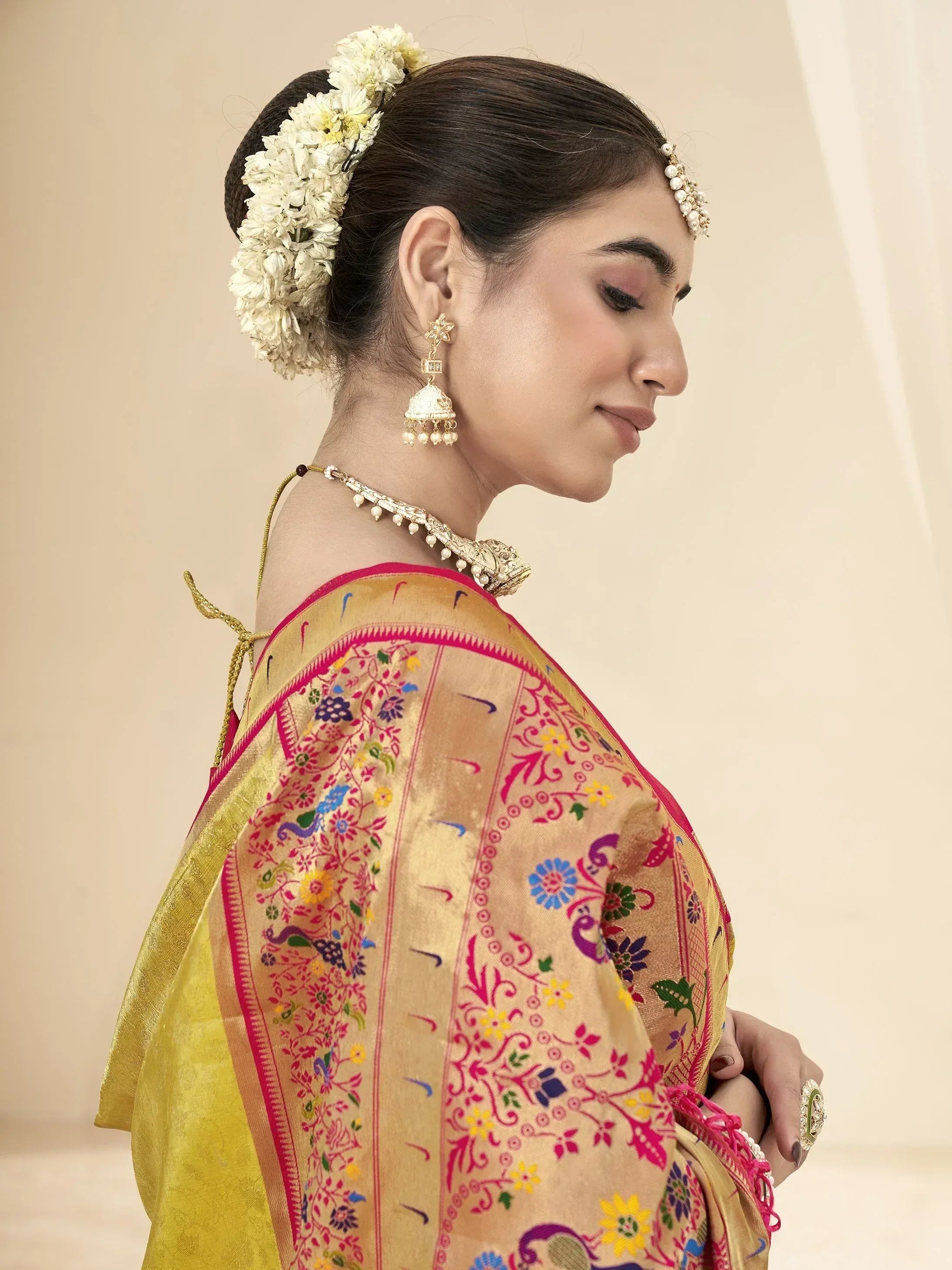 Woman in colorful embroidered saree with floral hair accessory and traditional jewelry